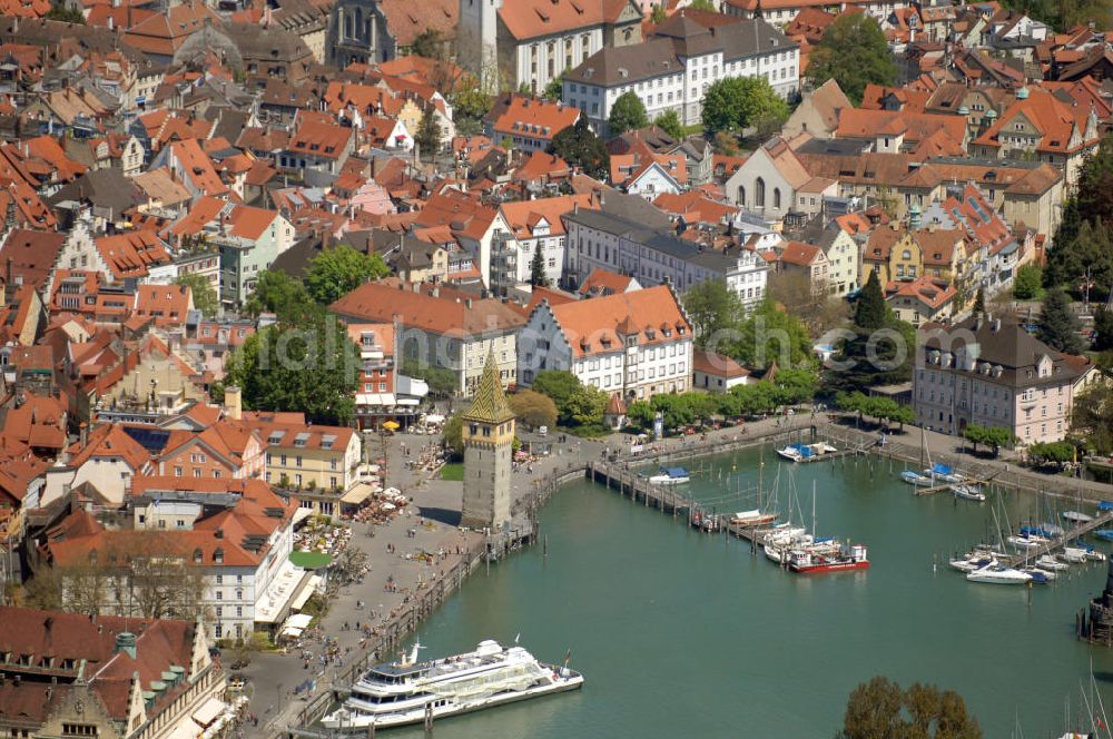 Lindau from the bird's eye view: Blick auf die Lindau Insel mit Hafen, Mangturm und Altstadt. Die Hafeneinfahrt an der Lindau Insel ist von einem Leuchtturm und dem Bayerischen Löwen begrenzt. Der Mangturm wurde um 1200 als Leuchtturm erbaut und war der Turm der ehemaligen Stadtbefestigung. Als besonderer Hingucker dient hier das bunte Dach, welches aus dem 19. Jhd. stammt. Seinen Namen hat er durch das ehemalige Tuch- und Manghaus, dass sich dort in der Nähe befand. Kontakt: Tourist-Information, Ludwigstraße 68, 88131 Lindau, Tel.: +49(0)8382 2600 30, Fax: +49(0)8382 2600 26, E-Mail: info@prolindau.de