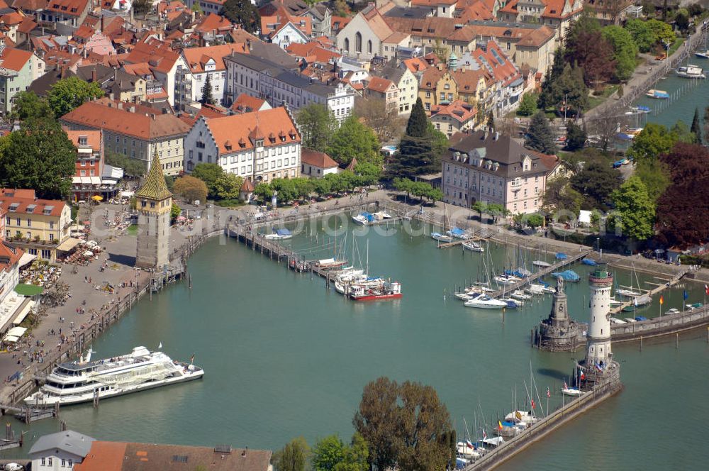 Aerial image Lindau - Blick auf die Lindau Insel mit Hafen, Mangturm und Altstadt. Die Hafeneinfahrt an der Lindau Insel ist von einem Leuchtturm und dem Bayerischen Löwen begrenzt. Der Mangturm wurde um 1200 als Leuchtturm erbaut und war der Turm der ehemaligen Stadtbefestigung. Als besonderer Hingucker dient hier das bunte Dach, welches aus dem 19. Jhd. stammt. Seinen Namen hat er durch das ehemalige Tuch- und Manghaus, dass sich dort in der Nähe befand. Kontakt: Tourist-Information, Ludwigstraße 68, 88131 Lindau, Tel.: +49(0)8382 2600 30, Fax: +49(0)8382 2600 26, E-Mail: info@prolindau.de