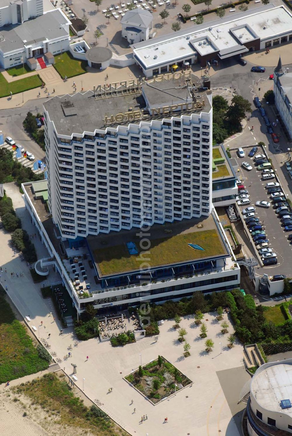 Aerial image Warnemünde - Blick auf das Hotel Neptun, ein direkt am Strand der Ostsee gelegenes 5-Sterne-Hotel im Ostseebad Warnemünde, das 1971 den Betrieb aufnahm. Das Hotel mit 338 Zimmern und dem ersten zertifizierten Thalassozentrum Deutschlandes gehört als „Wellness-Hotel“ zur Arkona AG, einer 100%igen Tochter der Deutschen Seereederei Rostock (DSR). Das ehem.Wohnungsbaukombinat Rostock und das schwedische Unternehmen SIAB errichteten von 1969 bis 1971 den 64 Meter hohen Betonklotz, der im Frühjahr 1971 eröffnet wurde. Die Architekten hatten den Bau so geplant, dass alle der rund 350 Zimmer mit Meeresblick waren. Neben den einheimischen Urlaubern übernachteten auch Geschäftsleute aus dem Westen gern in dem Prestige-Objekt. Hinzu kamen Staatsgäste wie Fidel Castro, aber auch westdeutsche Politiker wie Uwe Barschel und Willy Brandt. Für die Staatssicherheit der DDR eine gute Gelegenheit Informationen zu sammeln.