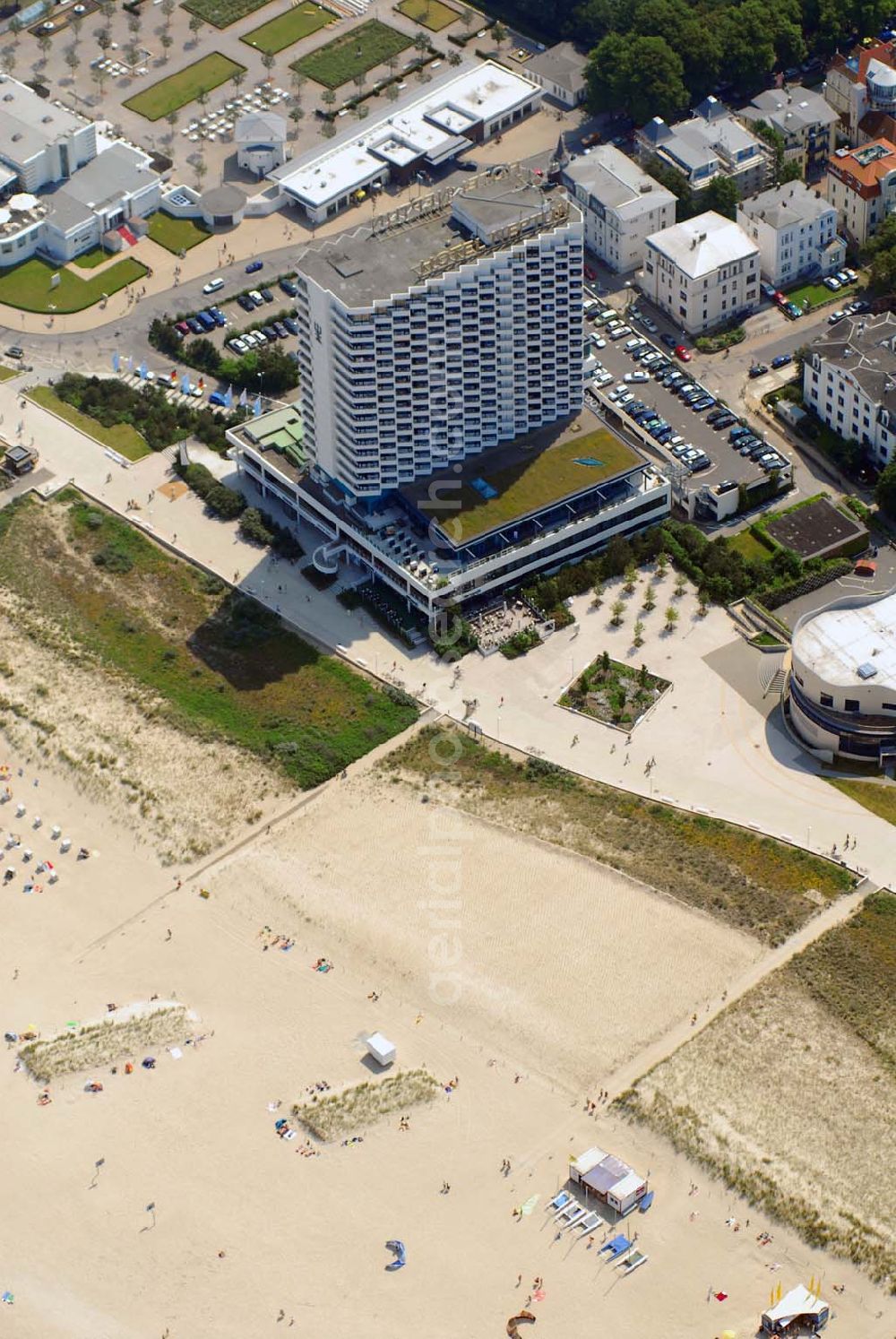 Aerial photograph Warnemünde - Blick auf das Hotel Neptun, ein direkt am Strand der Ostsee gelegenes 5-Sterne-Hotel im Ostseebad Warnemünde, das 1971 den Betrieb aufnahm. Das Hotel mit 338 Zimmern und dem ersten zertifizierten Thalassozentrum Deutschlandes gehört als „Wellness-Hotel“ zur Arkona AG, einer 100%igen Tochter der Deutschen Seereederei Rostock (DSR). Das ehem.Wohnungsbaukombinat Rostock und das schwedische Unternehmen SIAB errichteten von 1969 bis 1971 den 64 Meter hohen Betonklotz, der im Frühjahr 1971 eröffnet wurde. Die Architekten hatten den Bau so geplant, dass alle der rund 350 Zimmer mit Meeresblick waren. Neben den einheimischen Urlaubern übernachteten auch Geschäftsleute aus dem Westen gern in dem Prestige-Objekt. Hinzu kamen Staatsgäste wie Fidel Castro, aber auch westdeutsche Politiker wie Uwe Barschel und Willy Brandt. Für die Staatssicherheit der DDR eine gute Gelegenheit Informationen zu sammeln.