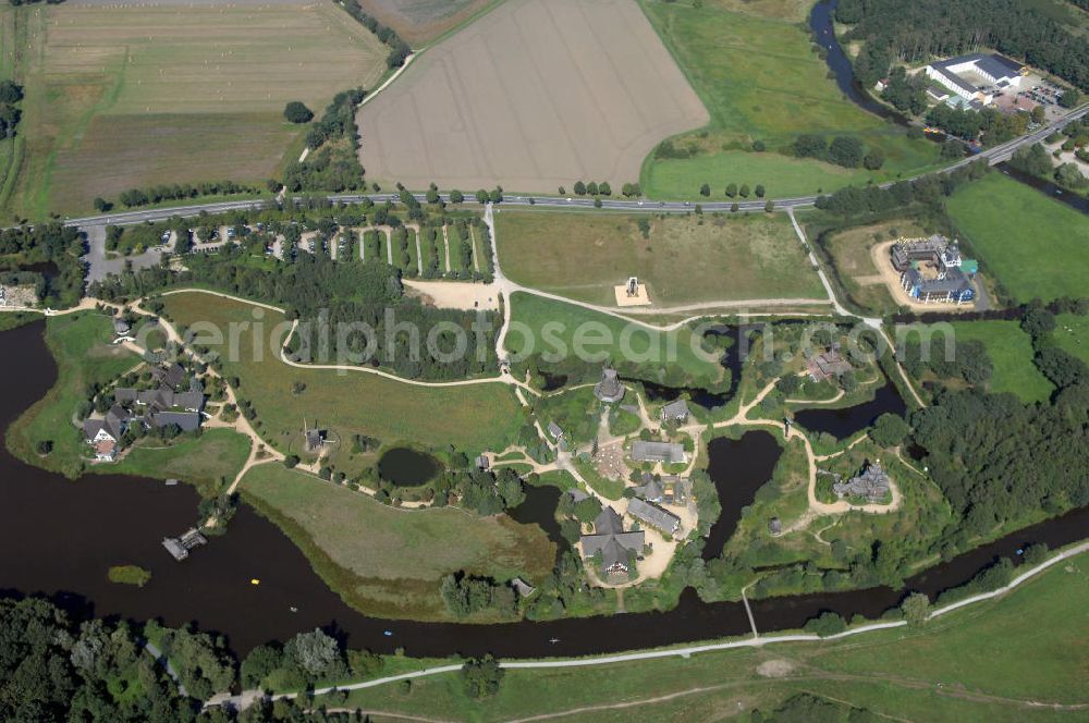 Gifhorn from the bird's eye view: Blick auf das Internationale Mühlenmuseum Gifhorn mit Mühlensee. Das Internationale Mühlenmuseum Gifhorn ist eine Einrichtung, die europaweit einzigartig ist. Das Freigelände des Museums ist ca. 16 ha groß. Auf diesem Gelände befinden sich derzeit 16 originale und originalgetreu nachgebaute Mühlen aus insgesamt 12 verschiedenen Ländern. Auch historische Gegenstände aus dem Mühlen- und Müllereiwesen sind auf dem ganzen Gelände ausgestellt. Das Museum wurde 1980 eröffnet. Durch Schwemmbaggern u. v. m. wurde das Gelände modeliert. Dabei entstand unter an derem auch der 5 ha große Mühlensee. Der See dient zur Wasserregulierung der Ise und als Rückhaltebecken für den Hochwasserschutz. Kontakt: Internationales Wind- und Wassermühlen-Museum, Bromer Straße 2, 38518 Gifhorn, Tel.: +49(0)537155 466, Fax: +49(0)537155 640