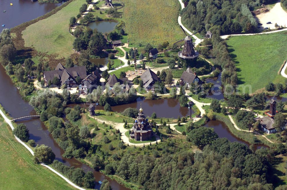 Aerial image Gifhorn - Blick auf das Internationale Mühlenmuseum Gifhorn mit Mühlensee. Das Internationale Mühlenmuseum Gifhorn ist eine Einrichtung, die europaweit einzigartig ist. Das Freigelände des Museums ist ca. 16 ha groß. Auf diesem Gelände befinden sich derzeit 16 originale und originalgetreu nachgebaute Mühlen aus insgesamt 12 verschiedenen Ländern. Auch historische Gegenstände aus dem Mühlen- und Müllereiwesen sind auf dem ganzen Gelände ausgestellt. Das Museum wurde 1980 eröffnet. Durch Schwemmbaggern u. v. m. wurde das Gelände modeliert. Dabei entstand unter an derem auch der 5 ha große Mühlensee. Der See dient zur Wasserregulierung der Ise und als Rückhaltebecken für den Hochwasserschutz. Kontakt: Internationales Wind- und Wassermühlen-Museum, Bromer Straße 2, 38518 Gifhorn, Tel.: +49(0)537155 466, Fax: +49(0)537155 640