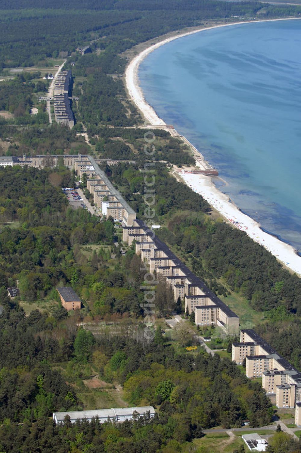 Aerial photograph Ostseebad Prora - Blick auf den „Koloss von Prora“ die 18m-Modellanlage KdF-Seebad Prora. Am 2. Mai 1936 fand die Grundsteinlegung des 1. von insgesamt 5 an der Nord und Ostseeküste geplanten Seebäder der 20.000 in Pora auf Rügen statt. Im November 1936 begannen 9 Baukonzerne und 48 Baufirmen mit ca. 5000 Arbeiter die Bauausführung, im Oktober 1938 konnte bereits Richtfest für das erste 500 m lange Unterkunftshaus gefeiert werden. Mit Kriegsbeginn 1939 wurden die Arbeiten auf der riesigen Großbaustelle stillgelegt. Nach 1945 wurden Teile des rohbauferigen KdF - Seebades demontiert und Abschnitte des Nordflügels von sowjetischen Truppen gesprengt. In den 50er Jahren übernahm die NVA der DDR das riesige Areal und baute es zu einem Militärstandort aus, etwa 10000 Soldaten und Offiziere waren ständig bis zur Auflösung 1990 in Prora kaserniert. Heute sind in dem historischen Gebäudekomplex u.a. folgende Einrichtungen untergebracht: Dokumentationszentrum der Stiftung NEUE KULTUR, das Museum zum Anfassen, KulturKunststatt Prora und die Grafik-Galerie.