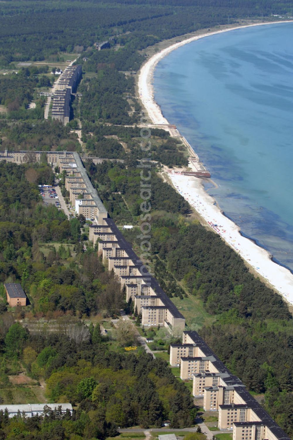 Ostseebad Prora from the bird's eye view: Blick auf den „Koloss von Prora“ die 18m-Modellanlage KdF-Seebad Prora. Am 2. Mai 1936 fand die Grundsteinlegung des 1. von insgesamt 5 an der Nord und Ostseeküste geplanten Seebäder der 20.000 in Pora auf Rügen statt. Im November 1936 begannen 9 Baukonzerne und 48 Baufirmen mit ca. 5000 Arbeiter die Bauausführung, im Oktober 1938 konnte bereits Richtfest für das erste 500 m lange Unterkunftshaus gefeiert werden. Mit Kriegsbeginn 1939 wurden die Arbeiten auf der riesigen Großbaustelle stillgelegt. Nach 1945 wurden Teile des rohbauferigen KdF - Seebades demontiert und Abschnitte des Nordflügels von sowjetischen Truppen gesprengt. In den 50er Jahren übernahm die NVA der DDR das riesige Areal und baute es zu einem Militärstandort aus, etwa 10000 Soldaten und Offiziere waren ständig bis zur Auflösung 1990 in Prora kaserniert. Heute sind in dem historischen Gebäudekomplex u.a. folgende Einrichtungen untergebracht: Dokumentationszentrum der Stiftung NEUE KULTUR, das Museum zum Anfassen, KulturKunststatt Prora und die Grafik-Galerie.