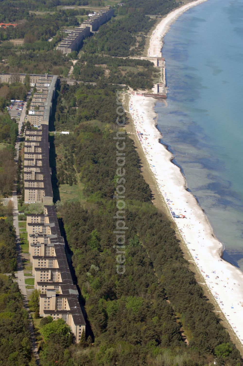 Ostseebad Prora from the bird's eye view: Blick auf den „Koloss von Prora“ die 18m-Modellanlage KdF-Seebad Prora. Am 2. Mai 1936 fand die Grundsteinlegung des 1. von insgesamt 5 an der Nord und Ostseeküste geplanten Seebäder der 20.000 in Pora auf Rügen statt. Im November 1936 begannen 9 Baukonzerne und 48 Baufirmen mit ca. 5000 Arbeiter die Bauausführung, im Oktober 1938 konnte bereits Richtfest für das erste 500 m lange Unterkunftshaus gefeiert werden. Mit Kriegsbeginn 1939 wurden die Arbeiten auf der riesigen Großbaustelle stillgelegt. Nach 1945 wurden Teile des rohbauferigen KdF - Seebades demontiert und Abschnitte des Nordflügels von sowjetischen Truppen gesprengt. In den 50er Jahren übernahm die NVA der DDR das riesige Areal und baute es zu einem Militärstandort aus, etwa 10000 Soldaten und Offiziere waren ständig bis zur Auflösung 1990 in Prora kaserniert. Heute sind in dem historischen Gebäudekomplex u.a. folgende Einrichtungen untergebracht: Dokumentationszentrum der Stiftung NEUE KULTUR, das Museum zum Anfassen, KulturKunststatt Prora und die Grafik-Galerie.