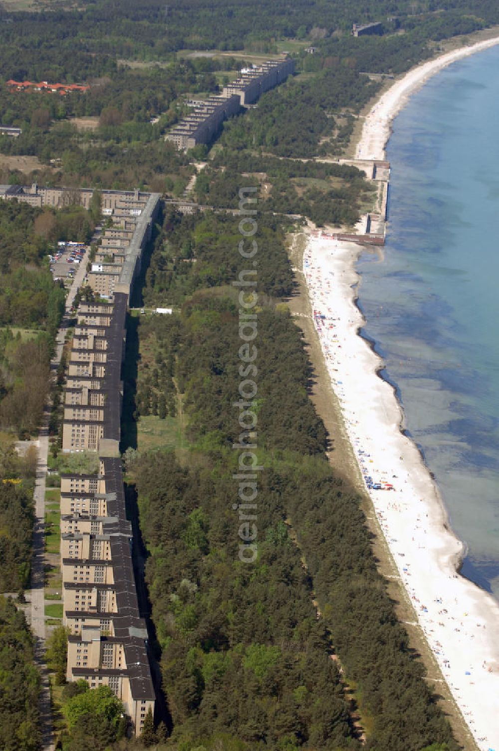 Aerial photograph Ostseebad Prora - Blick auf den „Koloss von Prora“ die 18m-Modellanlage KdF-Seebad Prora. Am 2. Mai 1936 fand die Grundsteinlegung des 1. von insgesamt 5 an der Nord und Ostseeküste geplanten Seebäder der 20.000 in Pora auf Rügen statt. Im November 1936 begannen 9 Baukonzerne und 48 Baufirmen mit ca. 5000 Arbeiter die Bauausführung, im Oktober 1938 konnte bereits Richtfest für das erste 500 m lange Unterkunftshaus gefeiert werden. Mit Kriegsbeginn 1939 wurden die Arbeiten auf der riesigen Großbaustelle stillgelegt. Nach 1945 wurden Teile des rohbauferigen KdF - Seebades demontiert und Abschnitte des Nordflügels von sowjetischen Truppen gesprengt. In den 50er Jahren übernahm die NVA der DDR das riesige Areal und baute es zu einem Militärstandort aus, etwa 10000 Soldaten und Offiziere waren ständig bis zur Auflösung 1990 in Prora kaserniert. Heute sind in dem historischen Gebäudekomplex u.a. folgende Einrichtungen untergebracht: Dokumentationszentrum der Stiftung NEUE KULTUR, das Museum zum Anfassen, KulturKunststatt Prora und die Grafik-Galerie.