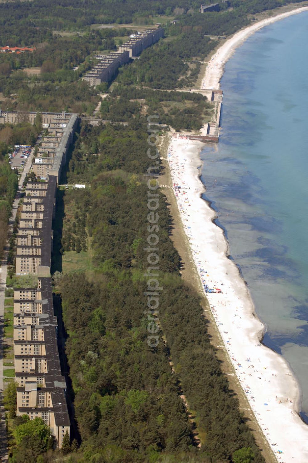 Ostseebad Prora from above - Blick auf den „Koloss von Prora“ die 18m-Modellanlage KdF-Seebad Prora. Am 2. Mai 1936 fand die Grundsteinlegung des 1. von insgesamt 5 an der Nord und Ostseeküste geplanten Seebäder der 20.000 in Pora auf Rügen statt. Im November 1936 begannen 9 Baukonzerne und 48 Baufirmen mit ca. 5000 Arbeiter die Bauausführung, im Oktober 1938 konnte bereits Richtfest für das erste 500 m lange Unterkunftshaus gefeiert werden. Mit Kriegsbeginn 1939 wurden die Arbeiten auf der riesigen Großbaustelle stillgelegt. Nach 1945 wurden Teile des rohbauferigen KdF - Seebades demontiert und Abschnitte des Nordflügels von sowjetischen Truppen gesprengt. In den 50er Jahren übernahm die NVA der DDR das riesige Areal und baute es zu einem Militärstandort aus, etwa 10000 Soldaten und Offiziere waren ständig bis zur Auflösung 1990 in Prora kaserniert. Heute sind in dem historischen Gebäudekomplex u.a. folgende Einrichtungen untergebracht: Dokumentationszentrum der Stiftung NEUE KULTUR, das Museum zum Anfassen, KulturKunststatt Prora und die Grafik-Galerie.