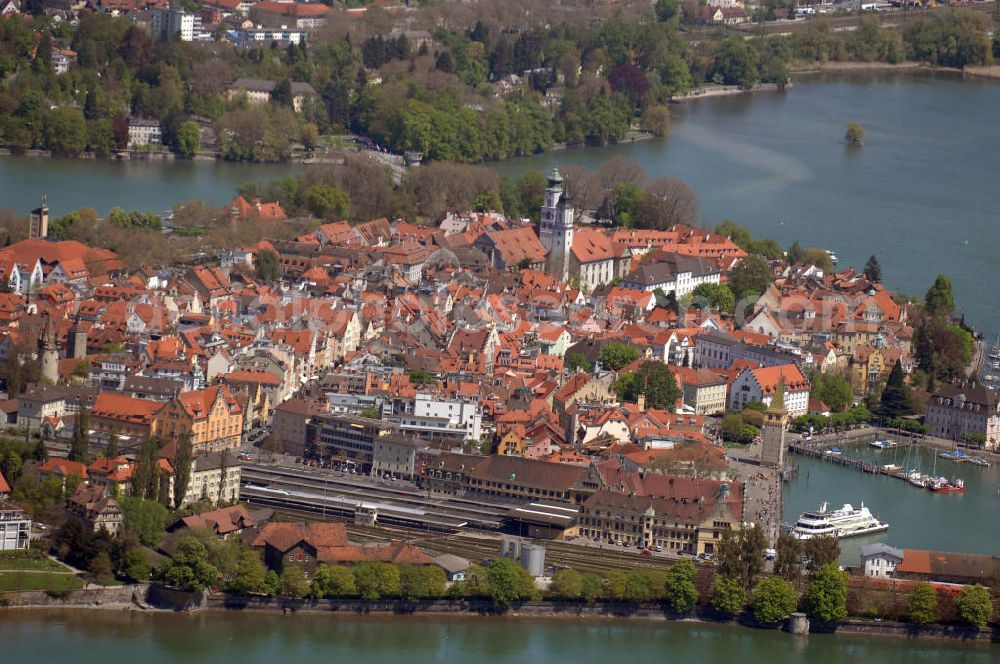 Aerial image Lindau - Blick auf die Lindau Insel mit Hafen, Kirche St. Stephan, Stiftskirche und Stadtbahnhof. Die Hafeneinfahrt an der Lindau Insel ist von einem Leuchtturm und dem Bayerischen Löwen begrenzt. Die evangelische Kirche St. Stephan ist die Schwesterkirche zur Stiftskirche. Der Stuck und die Altäre sind im Stil des Rokoko umgestaltet worden. Die Besonderheit der Kirche stellt das über 200 Jahre alte Gestühl dar. Die Stiftskirche oder auch Marienkirche genannt, wurde 1752 fertiggestellt. Sie ist ebenfalls im Stil des Rokoko ausgestattet. Der Stadtbahnhof wurde im Jugendstil von 1913 - 1921 erbaut. Durch eine schöne Boden- und Deckengestaltung zeichnet sich der Bahnhof ganz besonders aus. Kontakt: Tourist-Information, Ludwigstraße 68, 88131 Lindau, Tel.: +49(0)8382 2600 30, Fax: +49(0)8382 2600 26, E-Mail: info@prolindau.de