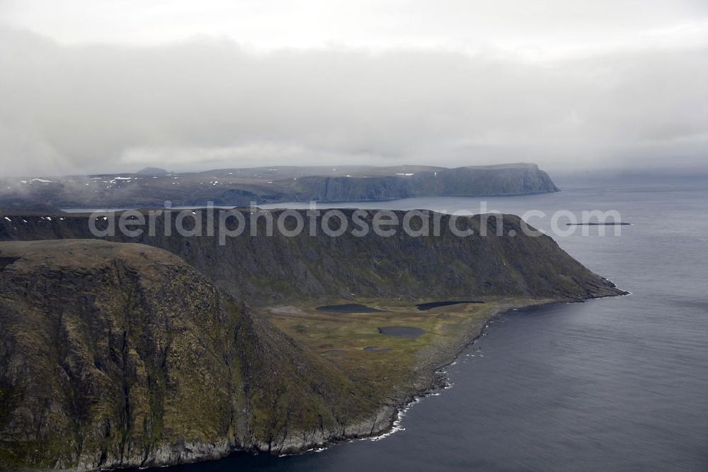 Nordkapp from the bird's eye view: Das Nordkapp (deutsch Nordkap) ein steil aus dem Eismeer emporragendes Schieferplateau. Obwohl das Nordkapp ist nicht der nördlichste Punkt Europas ist, dieser liegt 3 km westlich, ist es doch ein beliebtes Touristenziel.The Nordkapp is a towering steep slate from the Arctic Ocean Plateau. Although the North Cape is not the northernmost point of Europe, this is located 3 km to the west, it is nevertheless a popular tourist destination.