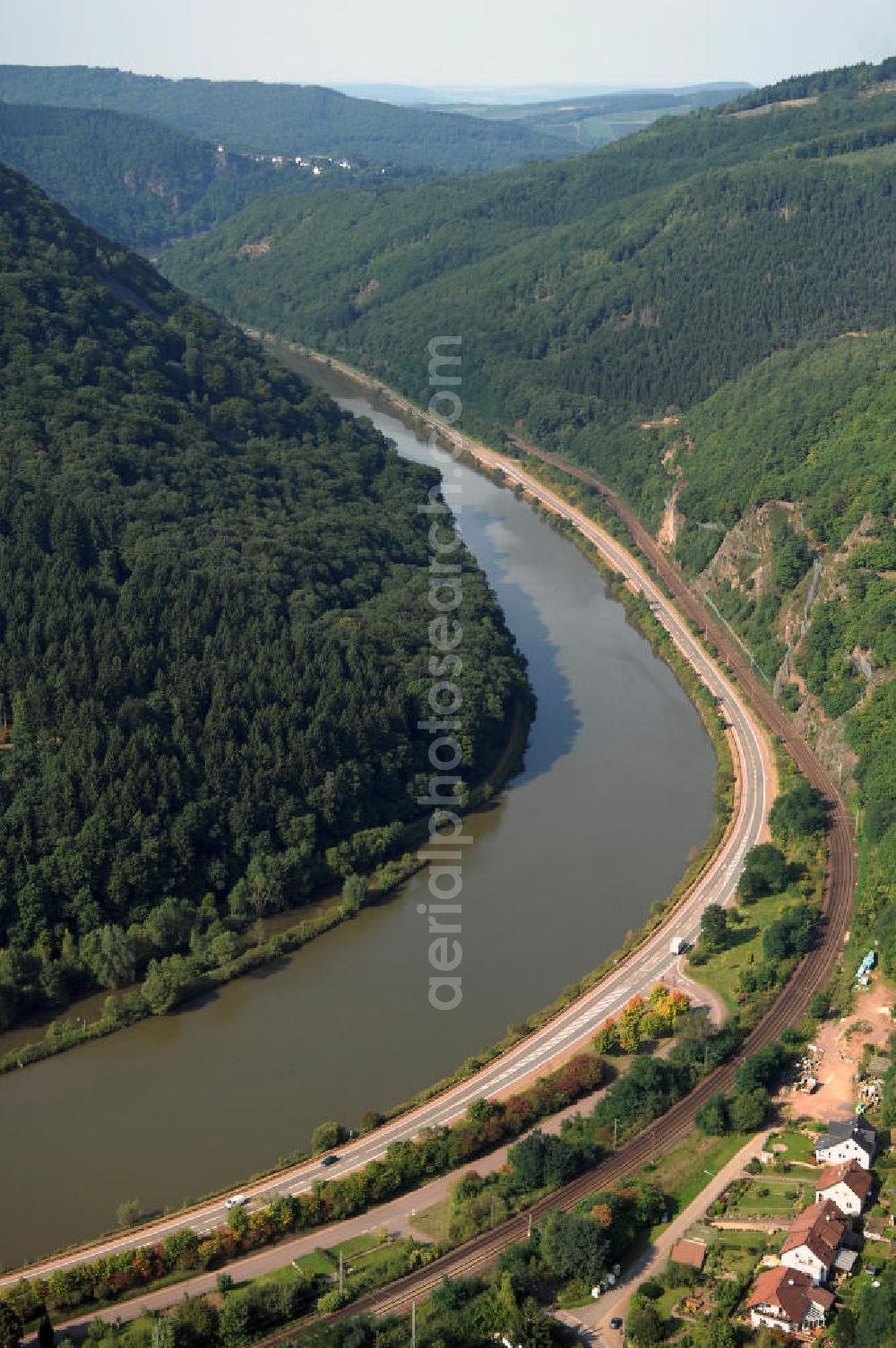 Saarhölzbach from above - Blick auf die Saar bei Saarhölzbach. Der Fluss hat eine Länge von 246 Kilometern und ist der größte Nebenfluss der Mosel. Am Donon in den Vogesen im Elsass in Frankreich entspringt die Saar, in Deutschland bei Konz mündet sie in die Mosel. Sie besteht aus zwei Quellflüssen - der roten und der weißen Saar, die bei Hermelange schließlich zusammenfließen. Bei Mettlach im Saarland, macht die Saar eine Schleife und fließt weiter nach Rheinland-Pfalz. Saarhölzbach ist ein Ortsteil der Gemeinde Mettlach und wurde erstmals 802 von Karl dem Großen unter dem Namen Hülzbach erwähnt. Touristisch interessant sind in Saarhölzbach der Aussichtspunkt Vogelfelsen, der Teufelsschornstein und die Kreuzkupp.