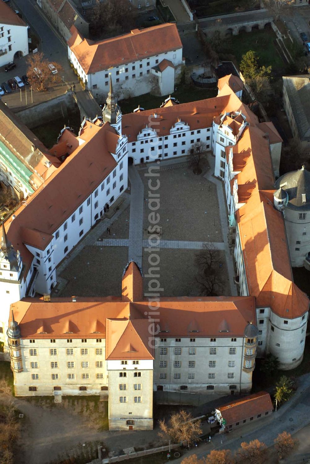 Aerial photograph Torgau - Blick auf Schloss Hartenfels an der Elbe. Es ist ein prachtvolles Renaissanceschloss in der Stadt Torgau im Freistaat Sachsen.Der Schlossbau wurde im 15. Jahrhundert von Konrad Pflüger, einem Schüler Arnolds von Westfalen begonnen und im 16. Jahrhundert von Konrad Krebs fortgeführt. Es war einer der Hofhaltungssitze der sächsischen Kurfürsten aus dem Hause Wettin und ist das größte vollständig erhaltene Schloss der Frührenaissance Deutschlands. Im Schlossinneren befindet sich der Wendelstein, eine fast 20 Meter hohe freitragende steinerne Wendeltreppe. Die Kapelle von Schloss Hartenfels war der erste protestantische Kirchenbau der Welt. Sie wurde 1544 von Martin Luther eingeweiht. Nachdem die albertinischen Wettiner im 16. Jahrhundert ihren Hofhaltungssitz dauerhaft nach Dresden verlegten, wurde das Schloss hauptsächlich als Verwaltungsgebäude genutzt. 1815 gelangte es an das Königreich Preußen und diente nunmehr der preußischen Verwaltung des neugebildeten Kreises Torgau.