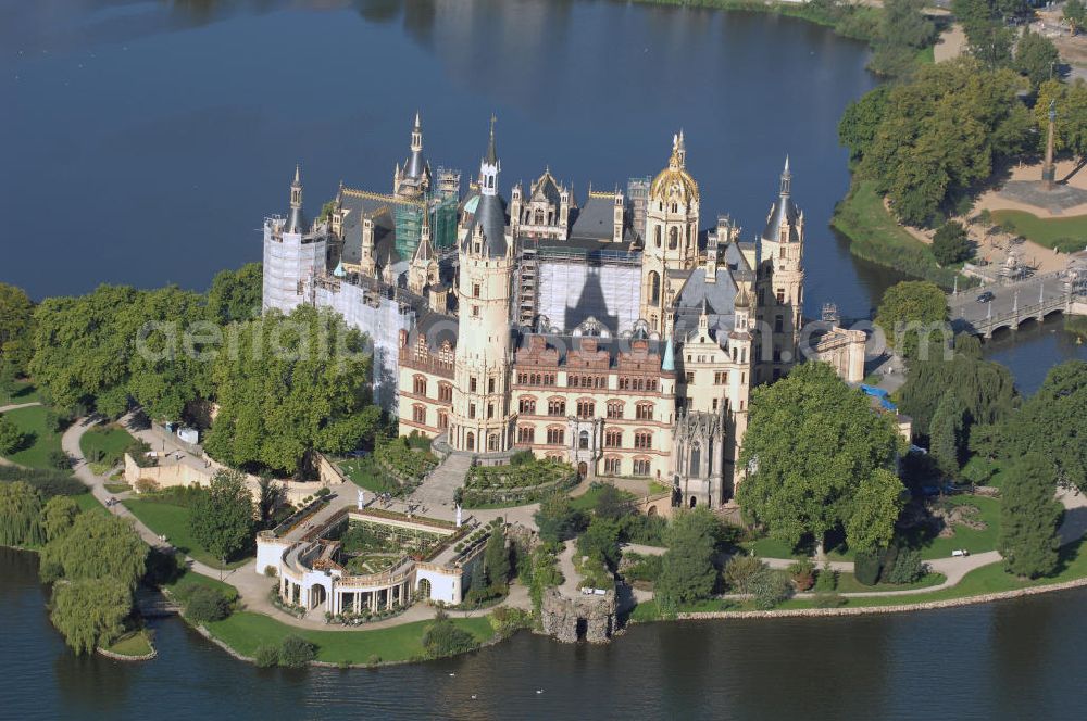 SCHWERIN from above - Blick über das Schweriner Schloss auf die Altstadt Schwerin. Das Schloss liegt auf der Schlossinsel im Stadtzentrum von Schwerin. Das Schloss ist ein in einem 1000jährigen Prozess historisch gewachsenes Bauwerk, dessen Gestalt auf eine Wallanlage einer slawischen Burg zurückgeht, die um das Jahr 965 auf einer Insel im Schweriner See errichtet wurde. Das heutige Schloss, das als Schlüsselwerk für die Gestaltungsweise des romantischen Historismus gilt, entstand durch einen tiefgreifenden Um- und Neubau des alten Schlosses in den Jahren 1845 bis 1857. Es war für lange Zeit Residenz der mecklenburgischen Herzöge und Großherzöge. Seit 1990 ist es Sitz des Landtages des Bundeslandes Mecklenburg-Vorpommern. Der als Museum genutzte Teil gehört zum Staatlichen Museum Schwerin. Kontakt: Landeshauptstadt Schwerin, Presse, Mareike Wolf, Am Packhof 2-6, 19053 Schwerin, Fax +49 (0)385 545 1019, Tel. +49 (0)385 545 1013, EMail mwolf@schwerin.de