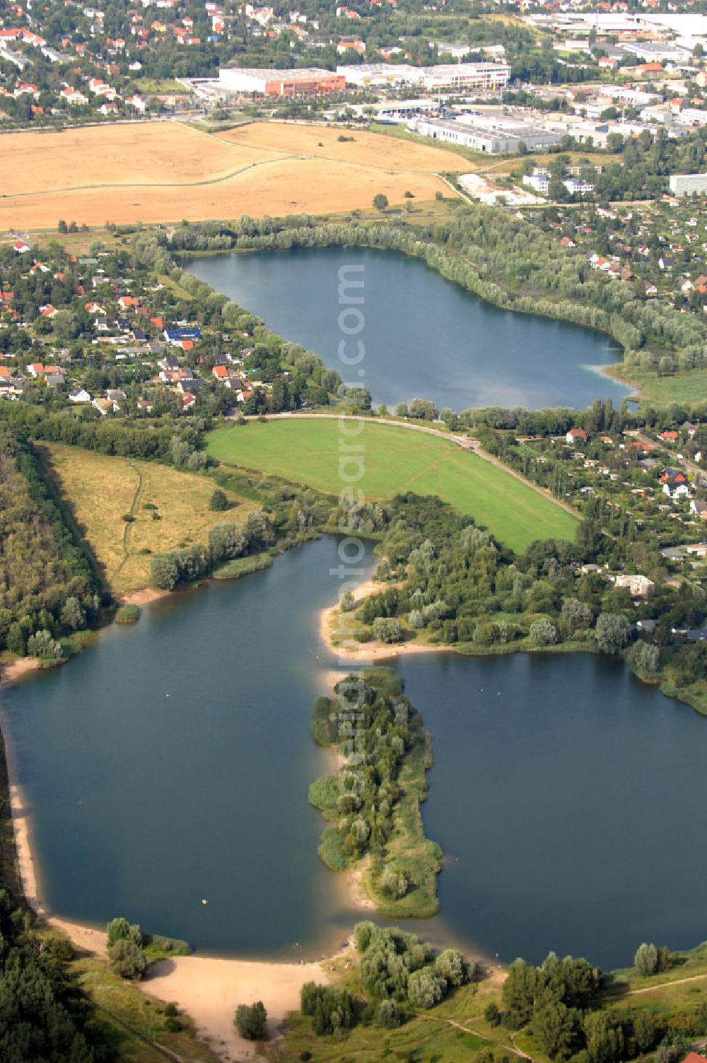 Berlin from the bird's eye view: Blick auf 2 Seen im Bezirk Marzahn-Hellersdorf. Im Vordergrund befindet sich mit dem Habermannsee und dem dahintergelegenen Kaulsdorfer Busch ein Teil der sogenannten Kaulsdorfer Seen, ein Landschaftsschutzgebiet im Ortsteil Kaulsdorf-Süd am Kressenweg, an dem sich mehrere Wongebiete entlangziehen. Der See in der Bildmitte ist der zu Mahlsdorf-Süd gehörende Elsensee an der Elsenstraße. Dahinter ist der Berliner Balkon zu sehen, ein unbebauter Hang an der Grenze zwischen Kaulsdorf und Mahlsdorf. Im oberen Teil des Bildes ist ein Gewerbegebiet an der B1 / Neuenhagener Straße zu erkennen, zu dem zum Beispiel eine Filiale des OBI-Baumarktes gehört.