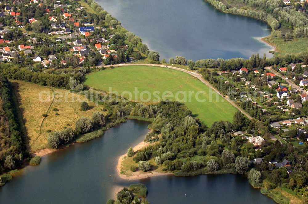 Aerial photograph Berlin - Blick auf 2 Seen im Bezirk Marzahn-Hellersdorf. Im Vordergrund befindet sich mit dem Habermannsee und dem dahintergelegenen Kaulsdorfer Busch ein Teil der sogenannten Kaulsdorfer Seen, ein Landschaftsschutzgebiet im Ortsteil Kaulsdorf-Süd am Kressenweg, an dem sich mehrere Wongebiete entlangziehen. Der See in der Bildmitte ist der zu Mahlsdorf-Süd gehörende Elsensee an der Elsenstraße. Dahinter ist der Berliner Balkon zu sehen, ein unbebauter Hang an der Grenze zwischen Kaulsdorf und Mahlsdorf. Im oberen Teil des Bildes ist ein Gewerbegebiet an der B1 / Neuenhagener Straße zu erkennen, zu dem zum Beispiel eine Filiale des OBI-Baumarktes gehört.