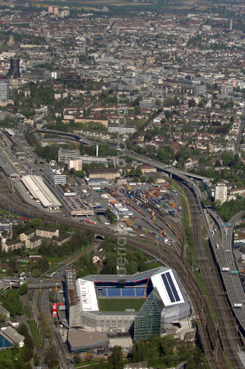 Aerial image Basel - Blick über die Stadt mit Stadion und Bahnhof. Der St. Jakob-Park (früher St. Jakob-Stadion, lokal Joggeli genannt) ist zur Zeit das grösste Fussballstadion der Schweiz und ist Teil des Sportzentrum St. Jakob. Es ist das Heimstadion des Fussballclub Basel (FCB). Es wurde von den Architekten Herzog & de Meuron von 1999 bis 2001 erstellt und hat ein Fassungsvermögen von 38500 Sitzplätzen. Es ist Austragungsort und Eröffnungsort der Europameisterschaft 2008. Zum St. Jakob-Park gehört auch der neu erbaute St.Jakob Turm mit Glasfassade.