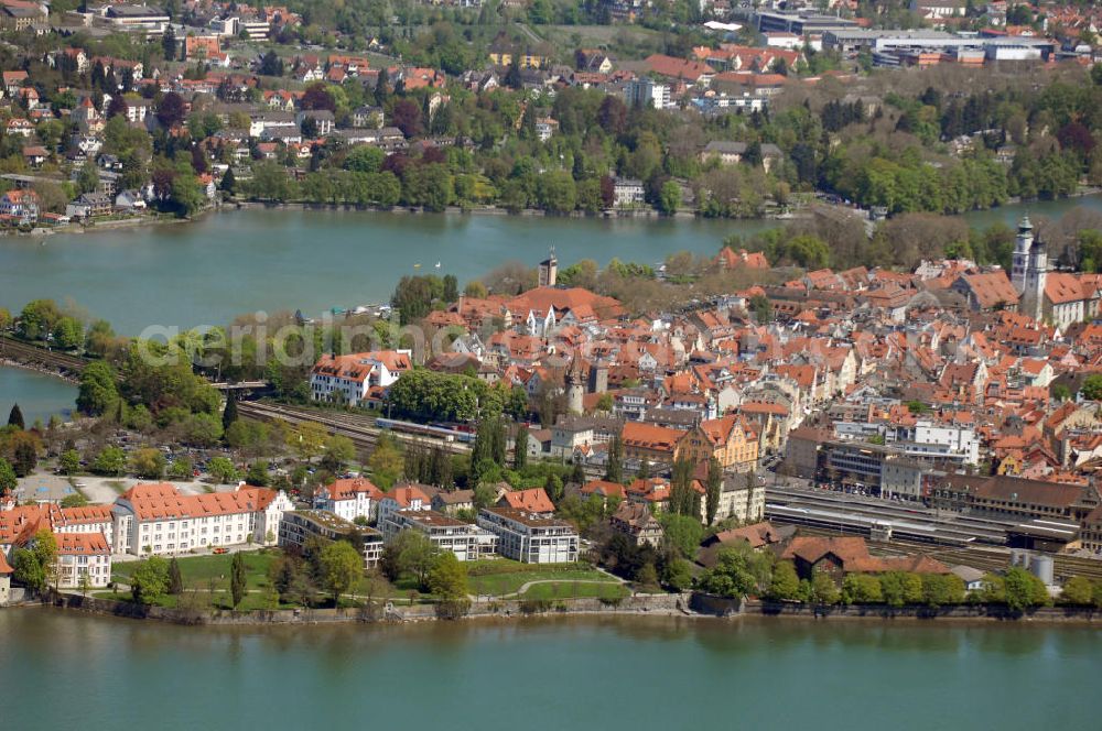 Lindau from the bird's eye view: Blick auf die Lindau Insel mit Hafen, Kirche St. Stephan, Stiftskirche und Stadtbahnhof. Die Hafeneinfahrt an der Lindau Insel ist von einem Leuchtturm und dem Bayerischen Löwen begrenzt. Die evangelische Kirche St. Stephan ist die Schwesterkirche zur Stiftskirche. Der Stuck und die Altäre sind im Stil des Rokoko umgestaltet worden. Die Besonderheit der Kirche stellt das über 200 Jahre alte Gestühl dar. Die Stiftskirche oder auch Marienkirche genannt, wurde 1752 fertiggestellt. Sie ist ebenfalls im Stil des Rokoko ausgestattet. Der Stadtbahnhof wurde im Jugendstil von 1913 - 1921 erbaut. Durch eine schöne Boden- und Deckengestaltung zeichnet sich der Bahnhof ganz besonders aus. Kontakt: Tourist-Information, Ludwigstraße 68, 88131 Lindau, Tel.: +49(0)8382 2600 30, Fax: +49(0)8382 2600 26, E-Mail: info@prolindau.de