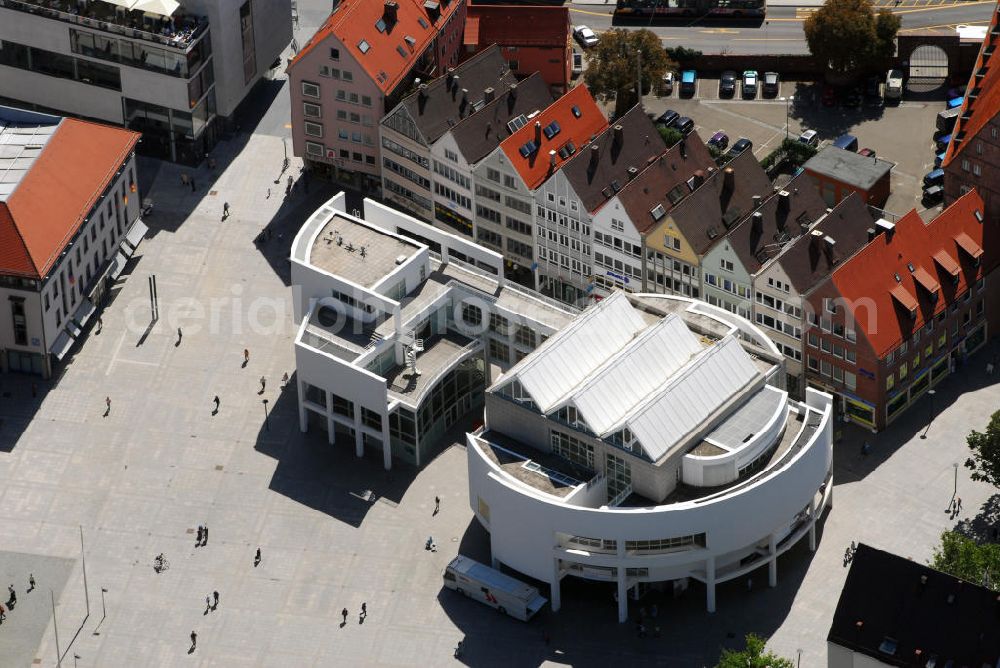 Aerial photograph Ulm - Blick auf das Stadthaus Ulm mit Café. Das Stadthaus befindet sich im Herzen Ulms auf dem Münsterplatz direkt vor dem höchsten Kirchturm der Welt, im weltberühmten Richard-Meier-Gebäude. Das Interieur des Cafés greift das Design der Klassisch-Modernen auf. Im November 1993 eröffnete Ulm einen neuen internationalen Markstein moderner Architektur: das Stadthaus. Der weiß verputzte und makellos geometrische, dreistöckige Pavillon verleiht dem Münsterplatz Klarheit und Schönheit, ohne dass dieser seinen reichen historischen Gehalt einbüßt. Das Stadthaus Ulm ist eines der wichtigsten europäischen Projekte Richard Meiers. Das Stadthaus produziert eigene Ausstellungen und kulturelle Veranstaltungen sowohl selbst als auch in Kooperation und versteht sich als Bürgerforum für Gastveranstaltungen. Es ist ein beliebter und vielgenutzter Treffpunkt. Je nach Anforderungsprofil einer Veranstaltung fungiert es als Ort für Ausstellungen, Konzerte, Diskussionsforen, Gesellschaftsabende oder als Kongresszentrum. Kontakt: Stadthaus, Münsterplatz 38, 89073 Ulm, Tel.: 0731 - 1617700, E-Mail: stadthaus@ulm.de