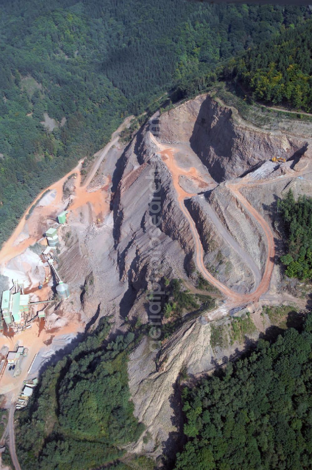 Saarhölzbach from above - Blick auf den Steinbruch bei Saarhölzbach in Rheinland-Pfalz. Der Steinbruch besteht aus Hartgestein, genauer aus Quarzit, das durch Sprengungen abgebaut und zu Schotter, Splitt und edelsplitt weiterverarbeitet wird. Auf Grund seiner Härte eignet es sich gut als Deckschicht im Straßenbau.