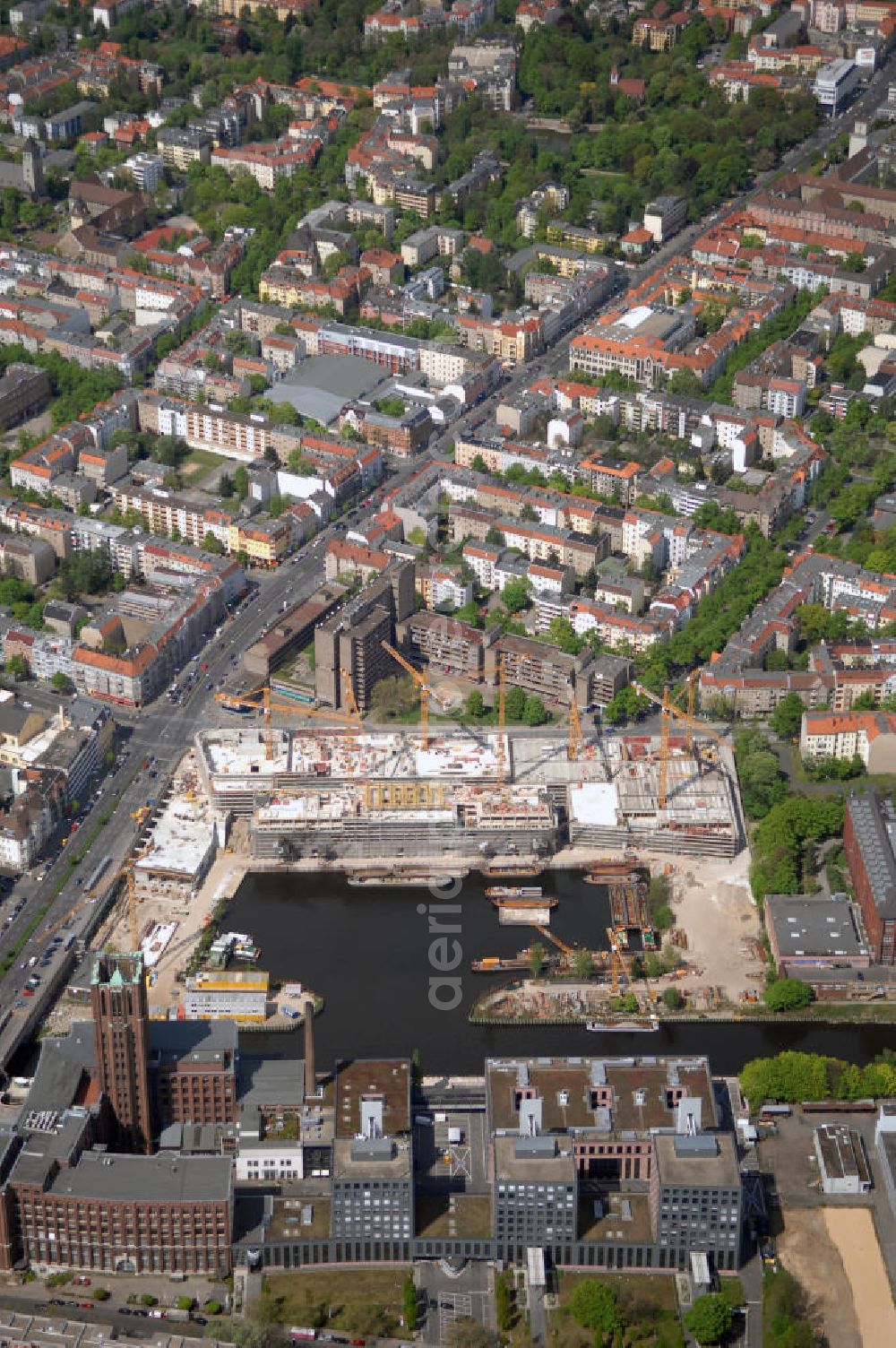 Aerial photograph Berlin - Blick auf die Baustelle vom Umbau Hafen Tempelhof am Ullsteinhaus. Der Tempelhofer Hafen entstand 1906 zusammen mit dem Teltowkanal. Zwei Jahre später kam der Speicher hinzu, eine der ersten Stahlbetonbauten in Deutschland. Im Krieg wurde das Gebäude schwer zerstört. Nach dem Wiederaufbau lagerte dort ein Teil der Lebensmittel-Reserve für West-Berlin. Bis zum Herbst 2008 sollen neben einer Einzelhandelsfläche von knapp 20 000 Quadratmetern und eine Fläche von etwa 10000 Quadratmeter für Unterhaltung, Grünflächen und Flanierwege entstehen. Hierfür wird der alte Speicher von einem Neubau flankiert. Etwa 70 Geschäfte haben in beiden Gebäuden Platz. Auf dem Dach des Neubaus entstehen 600 Parkplätze. Der Hafen selbst bleibt exklusiv Fußgängern und Freizeitkapitänen vorbehalten. Adresse: Ordensmeisterstraße, 12099 Berlin-Tempelhof; Kontakt Architekt: REM+tec Architekten, Gesellschaft für Projektentwicklung und Denkmalschutz mbH, Kurfürstenstraße 132, 10785 Berlin,Tel. 030 264767-70, Fax 030 264767-47, info@remtec.eu,