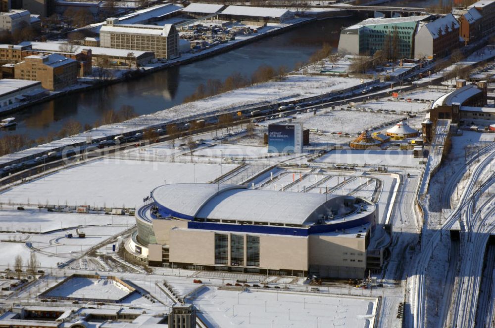 Berlin from above - Blick auf die o2 - Veranstaltungsarena in Berlin - Friedrichshain bei Schnee im Winter . Bei der O2 World handelt es sich um eine multifunktionale Veranstaltungshalle in Berlin zwischen Ostbahnhof und Warschauer Straße im Bezirk Friedrichshain-Kreuzberg. Die Grundsteinlegung erfolgte am 13. September 2006. In der Halle sollen Sportveranstaltungen wie Eishockey und Basketball, Sikveranstaltungen sowie viele weitere Events stattfinden. Bauherr und Investor ist die Anschutz Entertainment Group, die weltweit Arenen, Theater sowie verschiedene Tochterfirmen besitzt, betreibt und promotet. Die Firma O2 Germany hat die Namensrechte an der Arena in Berlin erworben.Mit bis zu 17.000 Sitz- und Stehplätzen, 59 Entertainment-Suiten soll die O2 World die größte Veranstaltungshalle Berlins werden und eine Vielzahl von Events ermöglichen.Für den Profi-Eishockeyclub Eisbären Berlin soll die Arena die neue sportliche Heimat werden.Anschrift: Anschutz Entertainment Group Q 207 Friedrichrichstraße 76,10117 Berlin,Tel.: +49 (0)30-20 60 70 80 Fax: +49 (0)30-20 60 70 81 11, presse@o2-world.de