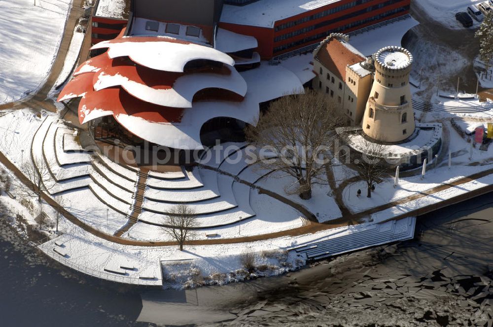 Aerial photograph POTSDAM - Blick auf das verschneite Hans Otto Theater, dem Brandenburgischen Landestheaters in Potsdam. Seit dem 22. September 2006 spielt das Ensemble in dem neuen Potsdamer Theaterhaus in der Schiffbauergasse am Ufer des Tiefen Sees.Der Architekt Gottfried Böhm entwarf ein fünfgeschossiges Theatergebäude mit schalenförmigen Dächern nach dem Vorbild des Sydney Opera House, die wie drei große Hutkrempen weit in das Ufer der Havel hineinzuragen scheinen. Ein alter Gasometer, der von einer Gasanstalt übrig geblieben ist, ist in die Architektur integriert und dient jetzt als Hof mit Wirtschaftsräumen. Beton und Glas sind die Materialien, die das Bauwerk charakterisieren.Das Obere Foyer und der Bühnensaal haben jeweils eine große Glasfensterfront, die der Bühne kann komplett abgedunkelt werden. Im Großen Saal ist für max. 480 Zuschauer Platz. Unter den Zuschauerreihen sind 50 Hubpodien angeordnet, mit denen das Auditorium gesenkt und gehoben werden kann. Die Hinterbühnen lassen sich weit öffnen, so dass man bis hinaus in den Innenraum des Gasometers schauen kann. BATEG Ingenieurbau GmbH - http://