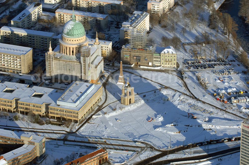 POTSDAM from above - Blick auf das verschneite Stadtzentrum am Alten Markt von Potsdam mit dem Hotel Mercure (vorn r.), der eingerüsteten evangelischen Kirche St. Nikolai (l.) und dem ebenfalls eingerüsteten Alten Rathaus (daneben r.), aufgenommen am 05.01.2009. In der Bildmitte die Baustelle für den künftigen Brandenburger Landtag auf dem Areal des früheren Stadtschlosses.