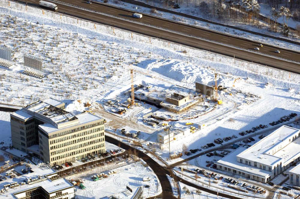 Aerial photograph Dreilinden - Blick auf den verschneiten Erweiterungsbaustelle Europapark Dreilinden bei der Waldsiedlung Dreilinden nahe der brandenburgischen Gemeinde Kleinmachnow (Landkreis Potsdam-Mittelmark) südwestlich von Berlin. Dreilinden ist der Name eines Forstes und einer Kolonie und war besonders bekannt als Bezeichnung für die frühere Grenzübergangsstelle Drewitz. Der ab 1990 errichtete Europapark ist ein Gewerbepark auf dem ehemaligen Gelände der wichtigsten Transitstrecke nach Westen und Süden (Checkpoint Bravo).