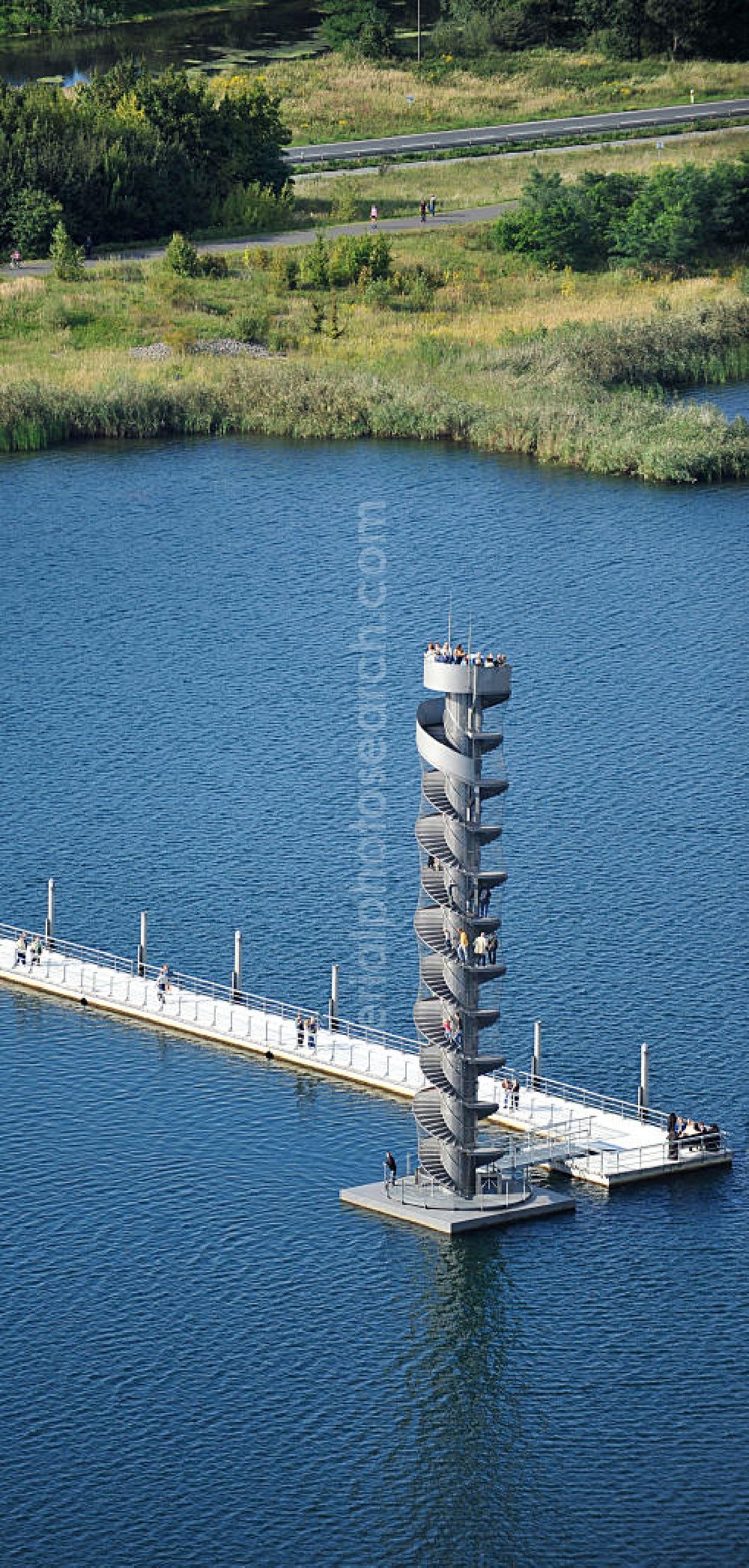 Bitterfeld from above - Blick auf das Wahrzeichen der Goitzsche, der Pegelturm mit Seebrücke im Goitzsche-See bei Bitterfeld, eine in Europa einmalige Seenlandschaft. Aus den Braunkohletagebauen Holzweißig West und Ost ist eine künstlich modellierte Kulturlandschaft entstanden.Insbesondere zur Expo 2000 entstandene Projekte haben die Goitzsche um eine kulturelle Dimension erweitert. Die Rückgewinnung einer Landschaft durch die Region und ihre Menschen sind die Sinn stiftenden Elemente der Bergbaufolge- und Kulturlandschaft Goitzsche. Gemeinsam gestalten die Ufergemeinden der Goitzsche ihre Ufer, entwickeln Flächen im Umland, verknüpfen Kunst, neue Architektur mit einprägsamer Landschaftsgestaltung. Goitzsche landmark, the tower level with the pier Goitzsche lake near Bitterfeld.