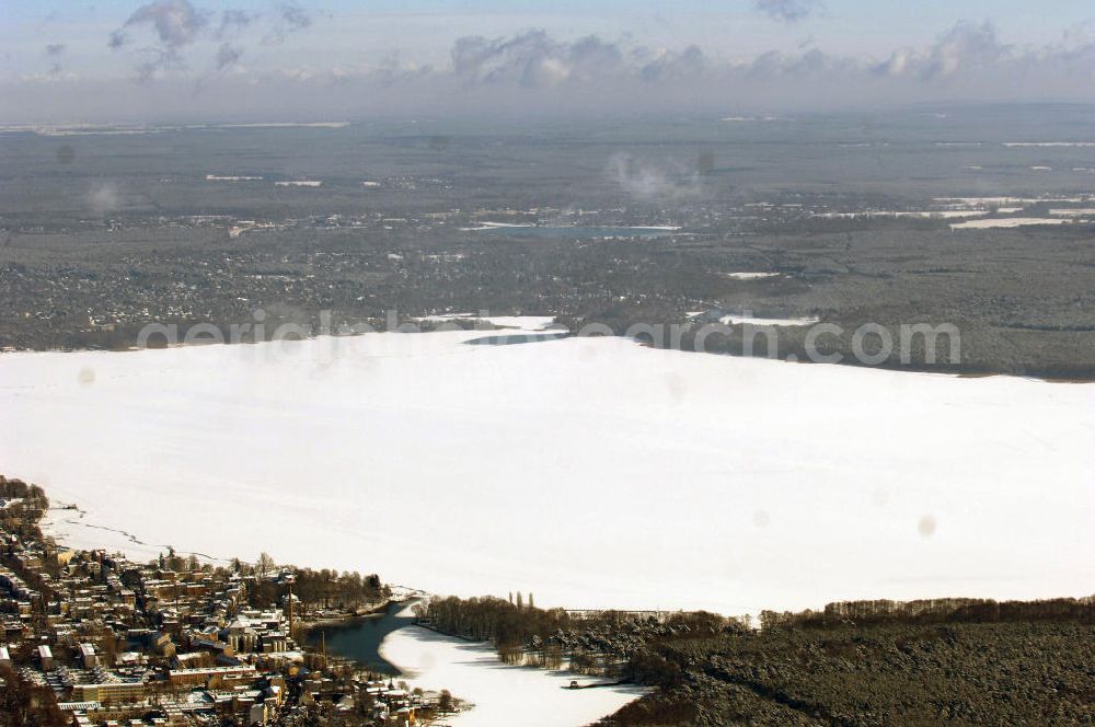 Aerial photograph Berlin - Blick auf das winterlich verschneite Areal des zugefrorenen Müggelsees. Der Müggelsee ist der größte der Berliner Seen. Zur Abgrenzung von dem mit ihm verbundenen, nur etwa 0,16 km² bedeckenden Kleinen Müggelsee wird er als Großer Müggelsee bezeichnet. Der Müggelsee gehört zum Berliner Bezirk Treptow-Köpenick, die Ortsteile Köpenick, Friedrichshagen, Rahnsdorf und Müggelheim grenzen an den See. Der See dehnt sich über 7,4 km² aus (max. 4,3 km lang; 2,6 km breit) und ist bis zu 8 Meter tief. Der See und die am Südrand gelegenen Müggelberge, mit 115 m die höchsten Berliner Erhebungen, entstanden während des Pleistozäns.