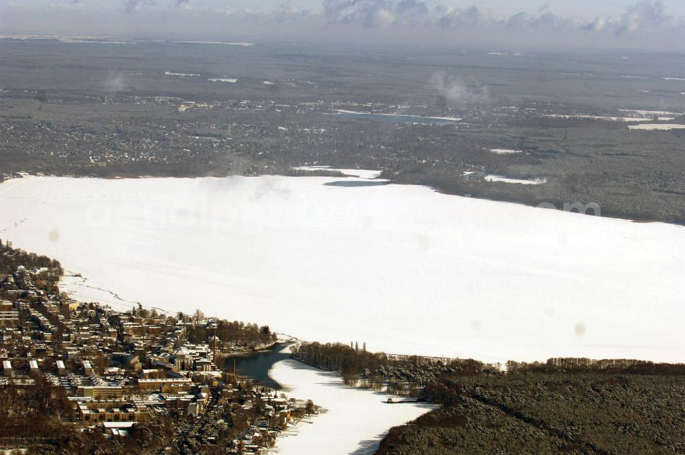 Berlin from above - Blick auf das winterlich verschneite Areal des zugefrorenen Müggelsees. Der Müggelsee ist der größte der Berliner Seen. Zur Abgrenzung von dem mit ihm verbundenen, nur etwa 0,16 km² bedeckenden Kleinen Müggelsee wird er als Großer Müggelsee bezeichnet. Der Müggelsee gehört zum Berliner Bezirk Treptow-Köpenick, die Ortsteile Köpenick, Friedrichshagen, Rahnsdorf und Müggelheim grenzen an den See. Der See dehnt sich über 7,4 km² aus (max. 4,3 km lang; 2,6 km breit) und ist bis zu 8 Meter tief. Der See und die am Südrand gelegenen Müggelberge, mit 115 m die höchsten Berliner Erhebungen, entstanden während des Pleistozäns.