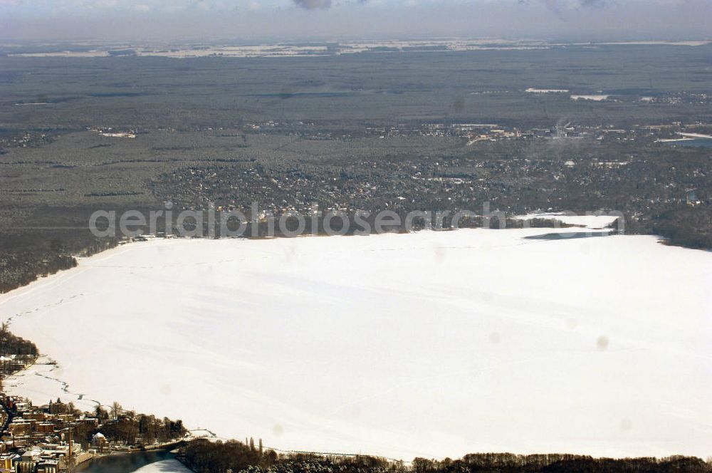 Aerial image Berlin - Blick auf das winterlich verschneite Areal des zugefrorenen Müggelsees. Der Müggelsee ist der größte der Berliner Seen. Zur Abgrenzung von dem mit ihm verbundenen, nur etwa 0,16 km² bedeckenden Kleinen Müggelsee wird er als Großer Müggelsee bezeichnet. Der Müggelsee gehört zum Berliner Bezirk Treptow-Köpenick, die Ortsteile Köpenick, Friedrichshagen, Rahnsdorf und Müggelheim grenzen an den See. Der See dehnt sich über 7,4 km² aus (max. 4,3 km lang; 2,6 km breit) und ist bis zu 8 Meter tief. Der See und die am Südrand gelegenen Müggelberge, mit 115 m die höchsten Berliner Erhebungen, entstanden während des Pleistozäns.