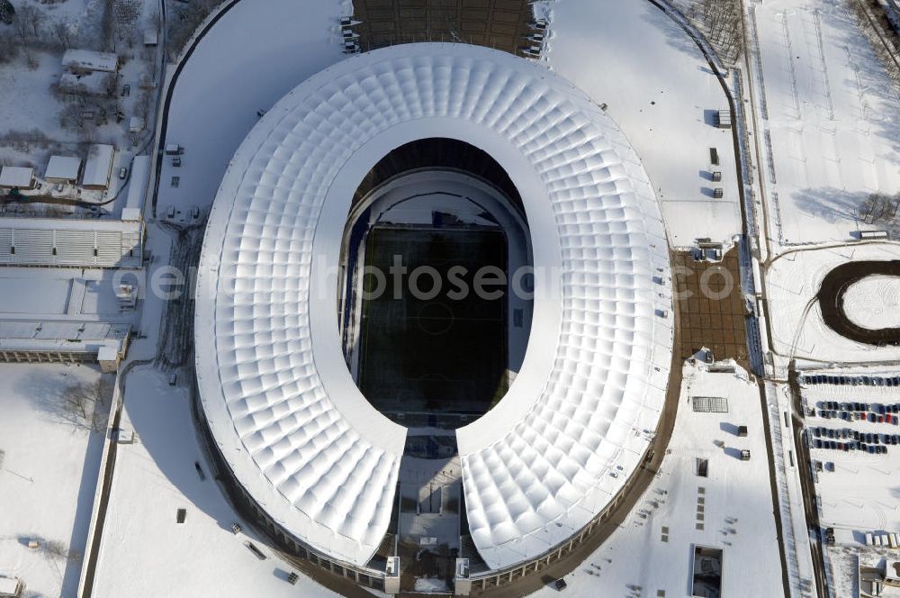 Aerial photograph Berlin - Blick auf das winterlich verschneite Olypiastadion Berlin. Das Olympiastadion wurde von 1934 bis 1936 anlässlich der Olympischen Sommerspiele 1936 mit einem Fassungsvermögen von 100.000 Zuschauern nach Plänen des Architekten Werner March erbaut.Seine Heimspiele trägt der Hauptnutzer, die Fußball-Bundesliga-Mannschaft von Hertha BSC, im Olympiastadion aus, und die jährlichen Endspiele um den DFB-Pokal der Damen und Herren finden hier seit 1985 statt. Das American-Football-Team von Berlin Thunder bestritt hier seine Heimspiele in der NFL Europe bis Juni 2007. Zusätzlich werden Leichtathletik-Wettkämpfe, wie das jährliche ISTAF, ausgetragen. Am 4. Dezember 2004 wurde Berlin zum Austragungsort der Leichtathletik-Weltmeisterschaft 2009 erkoren, die im Olympiastadion ausgetragen werden wird. Gelegentlich wird das Stadion auch für Großveranstaltungen ohne sportlichen Charakter, wie etwa Kirchentage oder Konzerte, genutzt. Das Olympiastadion besitzt die größte Stadionkapelle der Welt. http://