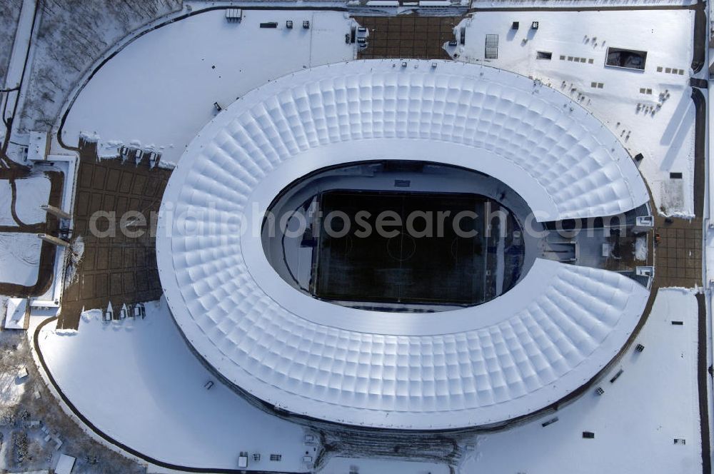 Berlin from the bird's eye view: Blick auf das winterlich verschneite Olypiastadion Berlin. Das Olympiastadion wurde von 1934 bis 1936 anlässlich der Olympischen Sommerspiele 1936 mit einem Fassungsvermögen von 100.000 Zuschauern nach Plänen des Architekten Werner March erbaut.Seine Heimspiele trägt der Hauptnutzer, die Fußball-Bundesliga-Mannschaft von Hertha BSC, im Olympiastadion aus, und die jährlichen Endspiele um den DFB-Pokal der Damen und Herren finden hier seit 1985 statt. Das American-Football-Team von Berlin Thunder bestritt hier seine Heimspiele in der NFL Europe bis Juni 2007. Zusätzlich werden Leichtathletik-Wettkämpfe, wie das jährliche ISTAF, ausgetragen. Am 4. Dezember 2004 wurde Berlin zum Austragungsort der Leichtathletik-Weltmeisterschaft 2009 erkoren, die im Olympiastadion ausgetragen werden wird. Gelegentlich wird das Stadion auch für Großveranstaltungen ohne sportlichen Charakter, wie etwa Kirchentage oder Konzerte, genutzt. Das Olympiastadion besitzt die größte Stadionkapelle der Welt. http://