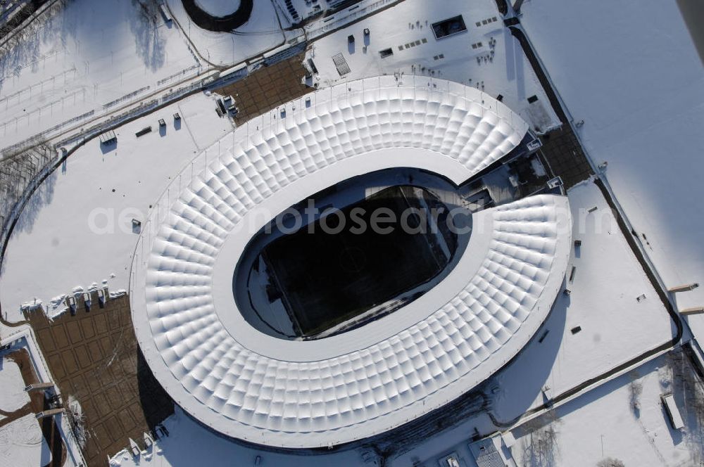 Aerial photograph Berlin - Blick auf das winterlich verschneite Olypiastadion Berlin. Das Olympiastadion wurde von 1934 bis 1936 anlässlich der Olympischen Sommerspiele 1936 mit einem Fassungsvermögen von 100.000 Zuschauern nach Plänen des Architekten Werner March erbaut.Seine Heimspiele trägt der Hauptnutzer, die Fußball-Bundesliga-Mannschaft von Hertha BSC, im Olympiastadion aus, und die jährlichen Endspiele um den DFB-Pokal der Damen und Herren finden hier seit 1985 statt. Das American-Football-Team von Berlin Thunder bestritt hier seine Heimspiele in der NFL Europe bis Juni 2007. Zusätzlich werden Leichtathletik-Wettkämpfe, wie das jährliche ISTAF, ausgetragen. Am 4. Dezember 2004 wurde Berlin zum Austragungsort der Leichtathletik-Weltmeisterschaft 2009 erkoren, die im Olympiastadion ausgetragen werden wird. Gelegentlich wird das Stadion auch für Großveranstaltungen ohne sportlichen Charakter, wie etwa Kirchentage oder Konzerte, genutzt. Das Olympiastadion besitzt die größte Stadionkapelle der Welt. http://