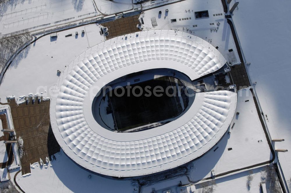 Berlin from above - Blick auf das winterlich verschneite Olypiastadion Berlin. Das Olympiastadion wurde von 1934 bis 1936 anlässlich der Olympischen Sommerspiele 1936 mit einem Fassungsvermögen von 100.000 Zuschauern nach Plänen des Architekten Werner March erbaut.Seine Heimspiele trägt der Hauptnutzer, die Fußball-Bundesliga-Mannschaft von Hertha BSC, im Olympiastadion aus, und die jährlichen Endspiele um den DFB-Pokal der Damen und Herren finden hier seit 1985 statt. Das American-Football-Team von Berlin Thunder bestritt hier seine Heimspiele in der NFL Europe bis Juni 2007. Zusätzlich werden Leichtathletik-Wettkämpfe, wie das jährliche ISTAF, ausgetragen. Am 4. Dezember 2004 wurde Berlin zum Austragungsort der Leichtathletik-Weltmeisterschaft 2009 erkoren, die im Olympiastadion ausgetragen werden wird. Gelegentlich wird das Stadion auch für Großveranstaltungen ohne sportlichen Charakter, wie etwa Kirchentage oder Konzerte, genutzt. Das Olympiastadion besitzt die größte Stadionkapelle der Welt. http://