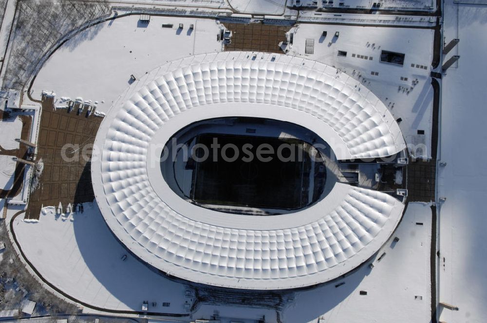 Berlin from the bird's eye view: Blick auf das winterlich verschneite Olypiastadion Berlin. Das Olympiastadion wurde von 1934 bis 1936 anlässlich der Olympischen Sommerspiele 1936 mit einem Fassungsvermögen von 100.000 Zuschauern nach Plänen des Architekten Werner March erbaut.Seine Heimspiele trägt der Hauptnutzer, die Fußball-Bundesliga-Mannschaft von Hertha BSC, im Olympiastadion aus, und die jährlichen Endspiele um den DFB-Pokal der Damen und Herren finden hier seit 1985 statt. Das American-Football-Team von Berlin Thunder bestritt hier seine Heimspiele in der NFL Europe bis Juni 2007. Zusätzlich werden Leichtathletik-Wettkämpfe, wie das jährliche ISTAF, ausgetragen. Am 4. Dezember 2004 wurde Berlin zum Austragungsort der Leichtathletik-Weltmeisterschaft 2009 erkoren, die im Olympiastadion ausgetragen werden wird. Gelegentlich wird das Stadion auch für Großveranstaltungen ohne sportlichen Charakter, wie etwa Kirchentage oder Konzerte, genutzt. Das Olympiastadion besitzt die größte Stadionkapelle der Welt. http://