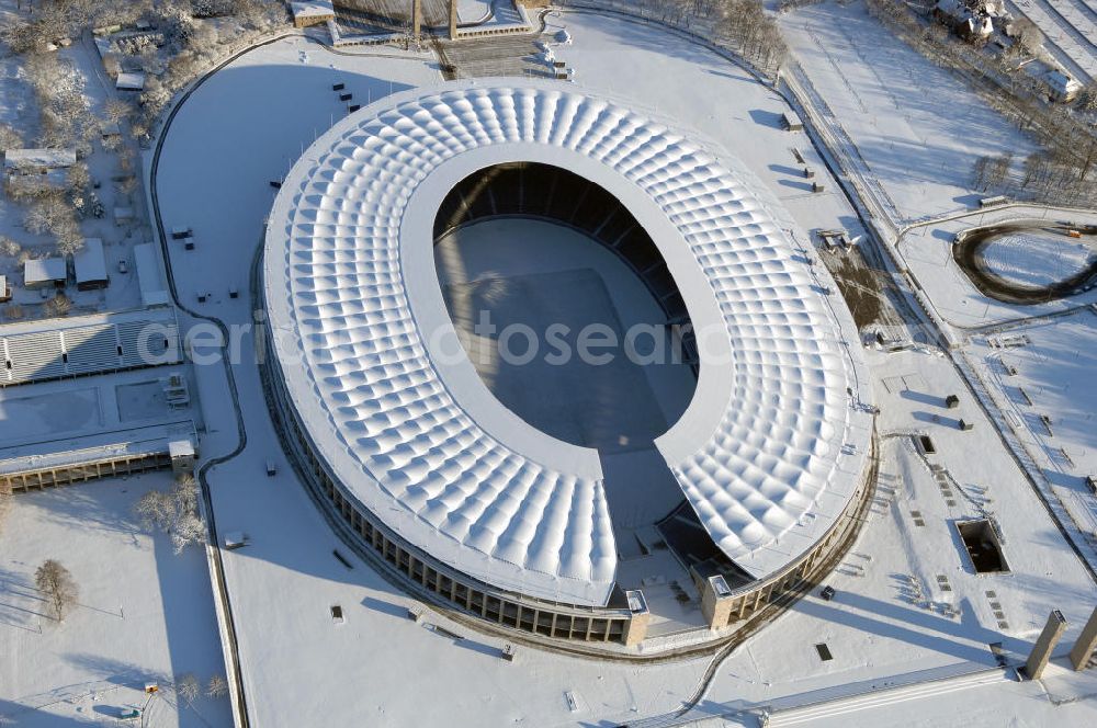 Berlin from the bird's eye view: Blick auf das winterlich verschneite Olypiastadion Berlin. Das Olympiastadion wurde von 1934 bis 1936 anlässlich der Olympischen Sommerspiele 1936 mit einem Fassungsvermögen von 100.000 Zuschauern nach Plänen des Architekten Werner March erbaut.Seine Heimspiele trägt der Hauptnutzer, die Fußball-Bundesliga-Mannschaft von Hertha BSC, im Olympiastadion aus, und die jährlichen Endspiele um den DFB-Pokal der Damen und Herren finden hier seit 1985 statt. Das American-Football-Team von Berlin Thunder bestritt hier seine Heimspiele in der NFL Europe bis Juni 2007. Zusätzlich werden Leichtathletik-Wettkämpfe, wie das jährliche ISTAF, ausgetragen. Am 4. Dezember 2004 wurde Berlin zum Austragungsort der Leichtathletik-Weltmeisterschaft 2009 erkoren, die im Olympiastadion ausgetragen werden wird. Gelegentlich wird das Stadion auch für Großveranstaltungen ohne sportlichen Charakter, wie etwa Kirchentage oder Konzerte, genutzt. Das Olympiastadion besitzt die größte Stadionkapelle der Welt. http://