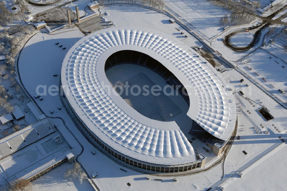 Aerial image Berlin - Blick auf das winterlich verschneite Olypiastadion Berlin. Das Olympiastadion wurde von 1934 bis 1936 anlässlich der Olympischen Sommerspiele 1936 mit einem Fassungsvermögen von 100.000 Zuschauern nach Plänen des Architekten Werner March erbaut.Seine Heimspiele trägt der Hauptnutzer, die Fußball-Bundesliga-Mannschaft von Hertha BSC, im Olympiastadion aus, und die jährlichen Endspiele um den DFB-Pokal der Damen und Herren finden hier seit 1985 statt. Das American-Football-Team von Berlin Thunder bestritt hier seine Heimspiele in der NFL Europe bis Juni 2007. Zusätzlich werden Leichtathletik-Wettkämpfe, wie das jährliche ISTAF, ausgetragen. Am 4. Dezember 2004 wurde Berlin zum Austragungsort der Leichtathletik-Weltmeisterschaft 2009 erkoren, die im Olympiastadion ausgetragen werden wird. Gelegentlich wird das Stadion auch für Großveranstaltungen ohne sportlichen Charakter, wie etwa Kirchentage oder Konzerte, genutzt. Das Olympiastadion besitzt die größte Stadionkapelle der Welt. http://