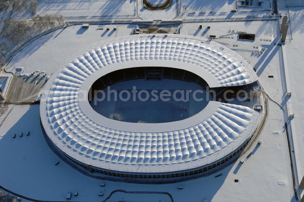 Aerial photograph Berlin - Blick auf das winterlich verschneite Olypiastadion Berlin. Das Olympiastadion wurde von 1934 bis 1936 anlässlich der Olympischen Sommerspiele 1936 mit einem Fassungsvermögen von 100.000 Zuschauern nach Plänen des Architekten Werner March erbaut.Seine Heimspiele trägt der Hauptnutzer, die Fußball-Bundesliga-Mannschaft von Hertha BSC, im Olympiastadion aus, und die jährlichen Endspiele um den DFB-Pokal der Damen und Herren finden hier seit 1985 statt. Das American-Football-Team von Berlin Thunder bestritt hier seine Heimspiele in der NFL Europe bis Juni 2007. Zusätzlich werden Leichtathletik-Wettkämpfe, wie das jährliche ISTAF, ausgetragen. Am 4. Dezember 2004 wurde Berlin zum Austragungsort der Leichtathletik-Weltmeisterschaft 2009 erkoren, die im Olympiastadion ausgetragen werden wird. Gelegentlich wird das Stadion auch für Großveranstaltungen ohne sportlichen Charakter, wie etwa Kirchentage oder Konzerte, genutzt. Das Olympiastadion besitzt die größte Stadionkapelle der Welt. http://