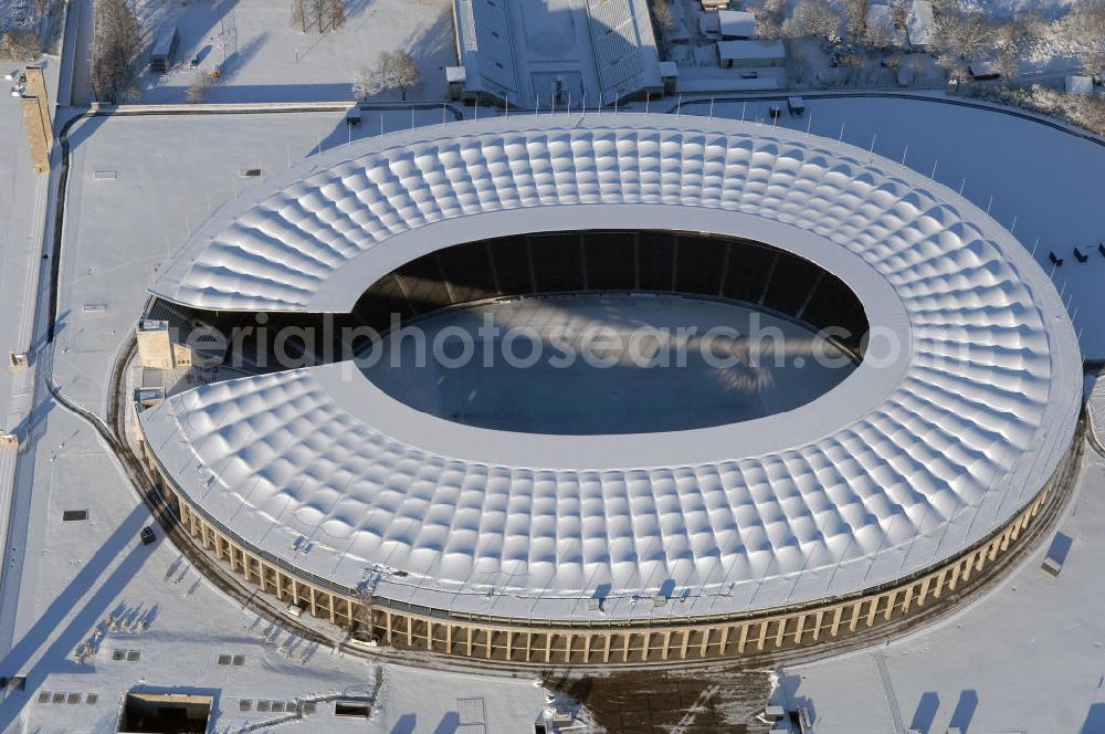 Aerial image Berlin - Blick auf das winterlich verschneite Olypiastadion Berlin. Das Olympiastadion wurde von 1934 bis 1936 anlässlich der Olympischen Sommerspiele 1936 mit einem Fassungsvermögen von 100.000 Zuschauern nach Plänen des Architekten Werner March erbaut.Seine Heimspiele trägt der Hauptnutzer, die Fußball-Bundesliga-Mannschaft von Hertha BSC, im Olympiastadion aus, und die jährlichen Endspiele um den DFB-Pokal der Damen und Herren finden hier seit 1985 statt. Das American-Football-Team von Berlin Thunder bestritt hier seine Heimspiele in der NFL Europe bis Juni 2007. Zusätzlich werden Leichtathletik-Wettkämpfe, wie das jährliche ISTAF, ausgetragen. Am 4. Dezember 2004 wurde Berlin zum Austragungsort der Leichtathletik-Weltmeisterschaft 2009 erkoren, die im Olympiastadion ausgetragen werden wird. Gelegentlich wird das Stadion auch für Großveranstaltungen ohne sportlichen Charakter, wie etwa Kirchentage oder Konzerte, genutzt. Das Olympiastadion besitzt die größte Stadionkapelle der Welt. http://