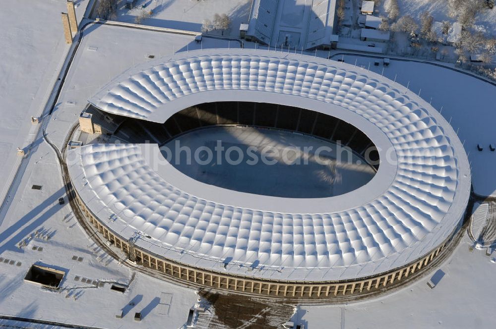 Aerial photograph Berlin - Blick auf das winterlich verschneite Olypiastadion Berlin. Das Olympiastadion wurde von 1934 bis 1936 anlässlich der Olympischen Sommerspiele 1936 mit einem Fassungsvermögen von 100.000 Zuschauern nach Plänen des Architekten Werner March erbaut.Seine Heimspiele trägt der Hauptnutzer, die Fußball-Bundesliga-Mannschaft von Hertha BSC, im Olympiastadion aus, und die jährlichen Endspiele um den DFB-Pokal der Damen und Herren finden hier seit 1985 statt. Das American-Football-Team von Berlin Thunder bestritt hier seine Heimspiele in der NFL Europe bis Juni 2007. Zusätzlich werden Leichtathletik-Wettkämpfe, wie das jährliche ISTAF, ausgetragen. Am 4. Dezember 2004 wurde Berlin zum Austragungsort der Leichtathletik-Weltmeisterschaft 2009 erkoren, die im Olympiastadion ausgetragen werden wird. Gelegentlich wird das Stadion auch für Großveranstaltungen ohne sportlichen Charakter, wie etwa Kirchentage oder Konzerte, genutzt. Das Olympiastadion besitzt die größte Stadionkapelle der Welt. http://