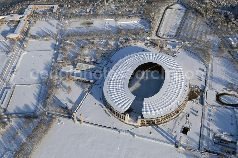 Aerial image Berlin - Blick auf das winterlich verschneite Olypiastadion Berlin. Das Olympiastadion wurde von 1934 bis 1936 anlässlich der Olympischen Sommerspiele 1936 mit einem Fassungsvermögen von 100.000 Zuschauern nach Plänen des Architekten Werner March erbaut.Seine Heimspiele trägt der Hauptnutzer, die Fußball-Bundesliga-Mannschaft von Hertha BSC, im Olympiastadion aus, und die jährlichen Endspiele um den DFB-Pokal der Damen und Herren finden hier seit 1985 statt. Das American-Football-Team von Berlin Thunder bestritt hier seine Heimspiele in der NFL Europe bis Juni 2007. Zusätzlich werden Leichtathletik-Wettkämpfe, wie das jährliche ISTAF, ausgetragen. Am 4. Dezember 2004 wurde Berlin zum Austragungsort der Leichtathletik-Weltmeisterschaft 2009 erkoren, die im Olympiastadion ausgetragen werden wird. Gelegentlich wird das Stadion auch für Großveranstaltungen ohne sportlichen Charakter, wie etwa Kirchentage oder Konzerte, genutzt. Das Olympiastadion besitzt die größte Stadionkapelle der Welt. http://