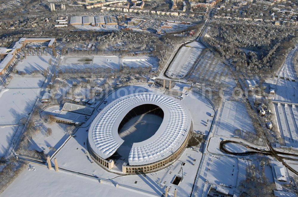 Aerial photograph Berlin - Blick auf das winterlich verschneite Olypiastadion Berlin. Das Olympiastadion wurde von 1934 bis 1936 anlässlich der Olympischen Sommerspiele 1936 mit einem Fassungsvermögen von 100.000 Zuschauern nach Plänen des Architekten Werner March erbaut.Seine Heimspiele trägt der Hauptnutzer, die Fußball-Bundesliga-Mannschaft von Hertha BSC, im Olympiastadion aus, und die jährlichen Endspiele um den DFB-Pokal der Damen und Herren finden hier seit 1985 statt. Das American-Football-Team von Berlin Thunder bestritt hier seine Heimspiele in der NFL Europe bis Juni 2007. Zusätzlich werden Leichtathletik-Wettkämpfe, wie das jährliche ISTAF, ausgetragen. Am 4. Dezember 2004 wurde Berlin zum Austragungsort der Leichtathletik-Weltmeisterschaft 2009 erkoren, die im Olympiastadion ausgetragen werden wird. Gelegentlich wird das Stadion auch für Großveranstaltungen ohne sportlichen Charakter, wie etwa Kirchentage oder Konzerte, genutzt. Das Olympiastadion besitzt die größte Stadionkapelle der Welt. http://