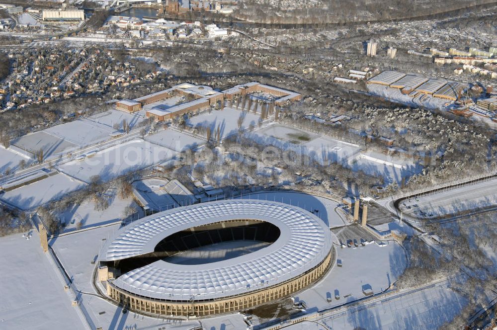 Aerial image Berlin - Blick auf das winterlich verschneite Olypiastadion Berlin. Das Olympiastadion wurde von 1934 bis 1936 anlässlich der Olympischen Sommerspiele 1936 mit einem Fassungsvermögen von 100.000 Zuschauern nach Plänen des Architekten Werner March erbaut.Seine Heimspiele trägt der Hauptnutzer, die Fußball-Bundesliga-Mannschaft von Hertha BSC, im Olympiastadion aus, und die jährlichen Endspiele um den DFB-Pokal der Damen und Herren finden hier seit 1985 statt. Das American-Football-Team von Berlin Thunder bestritt hier seine Heimspiele in der NFL Europe bis Juni 2007. Zusätzlich werden Leichtathletik-Wettkämpfe, wie das jährliche ISTAF, ausgetragen. Am 4. Dezember 2004 wurde Berlin zum Austragungsort der Leichtathletik-Weltmeisterschaft 2009 erkoren, die im Olympiastadion ausgetragen werden wird. Gelegentlich wird das Stadion auch für Großveranstaltungen ohne sportlichen Charakter, wie etwa Kirchentage oder Konzerte, genutzt. Das Olympiastadion besitzt die größte Stadionkapelle der Welt. http://