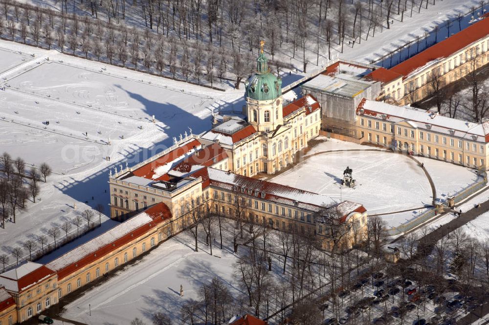 Berlin from the bird's eye view: Blick auf den winterlich verschneite Schloß Charlottenburg. Die spätere Schlossinsel Köpenick wurde schon zu urgeschichtlicher Zeit besiedelt und ist neben Spandau und Cölln eine der frühesten Siedlungsgebiete des heutigen Berlins. Hier fanden sich später slawische Burgwälle, eine slawische Burg entstand im 8. oder 9. Jahrhundert. Mehrere Nachfolgebauten folgten, darunter auch eine spätmittelalterliche Kastellburg. Der Slawenfürst Jaxa von Köpenick regierte hier im 12. Jahrhundert.Für Kurprinz Friedrich (später Kurfürst Friedrich III. von Brandenburg, dann auch König Friedrich I. in Preußen) wurde das Schloss ab 1677 erweitert. Als Architekt war hierbei Rutger van Langervelt, ein geborener Holländer aus Nimwegen, verantwortlich. Der nördliche Pavillon entstand in den Jahren 1679–1682. Der Architekt Johann Arnold Nering folgte van Langervelt 1684 beim Schlossbau und ließ den Wirtschaftsflügel mit der reformierten Schlosskirche (eingeweiht am 6. Januar 1685) und zuvor bereits das Hoftor (1682) entstehen. Friedrich bewohnte das Schloss später mit seiner Gemahlin Elisabeth Henriette von Hessen-Kassel, die den Anstoß zum Bau der Kirche gegeben haben soll.