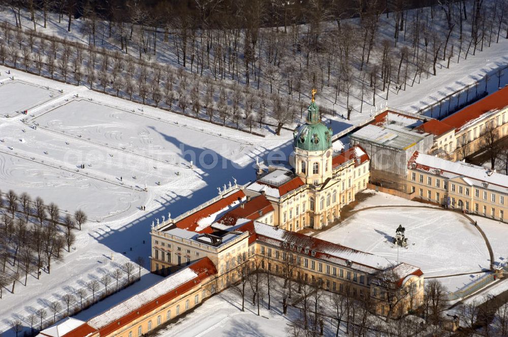 Aerial image Berlin - Blick auf den winterlich verschneite Schloß Charlottenburg. Die spätere Schlossinsel Köpenick wurde schon zu urgeschichtlicher Zeit besiedelt und ist neben Spandau und Cölln eine der frühesten Siedlungsgebiete des heutigen Berlins. Hier fanden sich später slawische Burgwälle, eine slawische Burg entstand im 8. oder 9. Jahrhundert. Mehrere Nachfolgebauten folgten, darunter auch eine spätmittelalterliche Kastellburg. Der Slawenfürst Jaxa von Köpenick regierte hier im 12. Jahrhundert.Für Kurprinz Friedrich (später Kurfürst Friedrich III. von Brandenburg, dann auch König Friedrich I. in Preußen) wurde das Schloss ab 1677 erweitert. Als Architekt war hierbei Rutger van Langervelt, ein geborener Holländer aus Nimwegen, verantwortlich. Der nördliche Pavillon entstand in den Jahren 1679–1682. Der Architekt Johann Arnold Nering folgte van Langervelt 1684 beim Schlossbau und ließ den Wirtschaftsflügel mit der reformierten Schlosskirche (eingeweiht am 6. Januar 1685) und zuvor bereits das Hoftor (1682) entstehen. Friedrich bewohnte das Schloss später mit seiner Gemahlin Elisabeth Henriette von Hessen-Kassel, die den Anstoß zum Bau der Kirche gegeben haben soll.