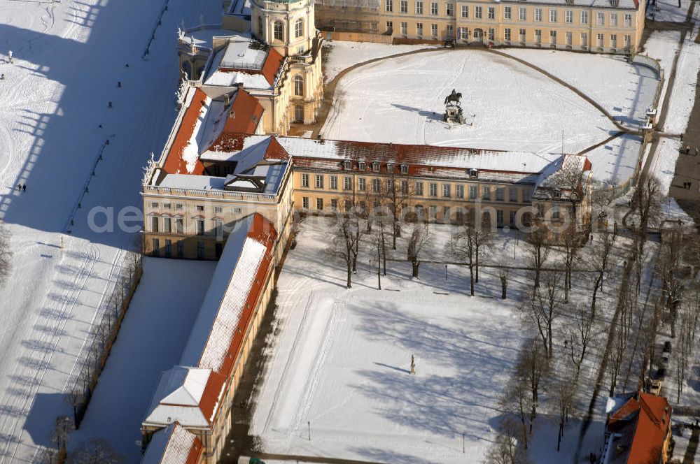 Aerial photograph Berlin - Blick auf den winterlich verschneite Schloß Charlottenburg. Die spätere Schlossinsel Köpenick wurde schon zu urgeschichtlicher Zeit besiedelt und ist neben Spandau und Cölln eine der frühesten Siedlungsgebiete des heutigen Berlins. Hier fanden sich später slawische Burgwälle, eine slawische Burg entstand im 8. oder 9. Jahrhundert. Mehrere Nachfolgebauten folgten, darunter auch eine spätmittelalterliche Kastellburg. Der Slawenfürst Jaxa von Köpenick regierte hier im 12. Jahrhundert.Für Kurprinz Friedrich (später Kurfürst Friedrich III. von Brandenburg, dann auch König Friedrich I. in Preußen) wurde das Schloss ab 1677 erweitert. Als Architekt war hierbei Rutger van Langervelt, ein geborener Holländer aus Nimwegen, verantwortlich. Der nördliche Pavillon entstand in den Jahren 1679–1682. Der Architekt Johann Arnold Nering folgte van Langervelt 1684 beim Schlossbau und ließ den Wirtschaftsflügel mit der reformierten Schlosskirche (eingeweiht am 6. Januar 1685) und zuvor bereits das Hoftor (1682) entstehen. Friedrich bewohnte das Schloss später mit seiner Gemahlin Elisabeth Henriette von Hessen-Kassel, die den Anstoß zum Bau der Kirche gegeben haben soll.