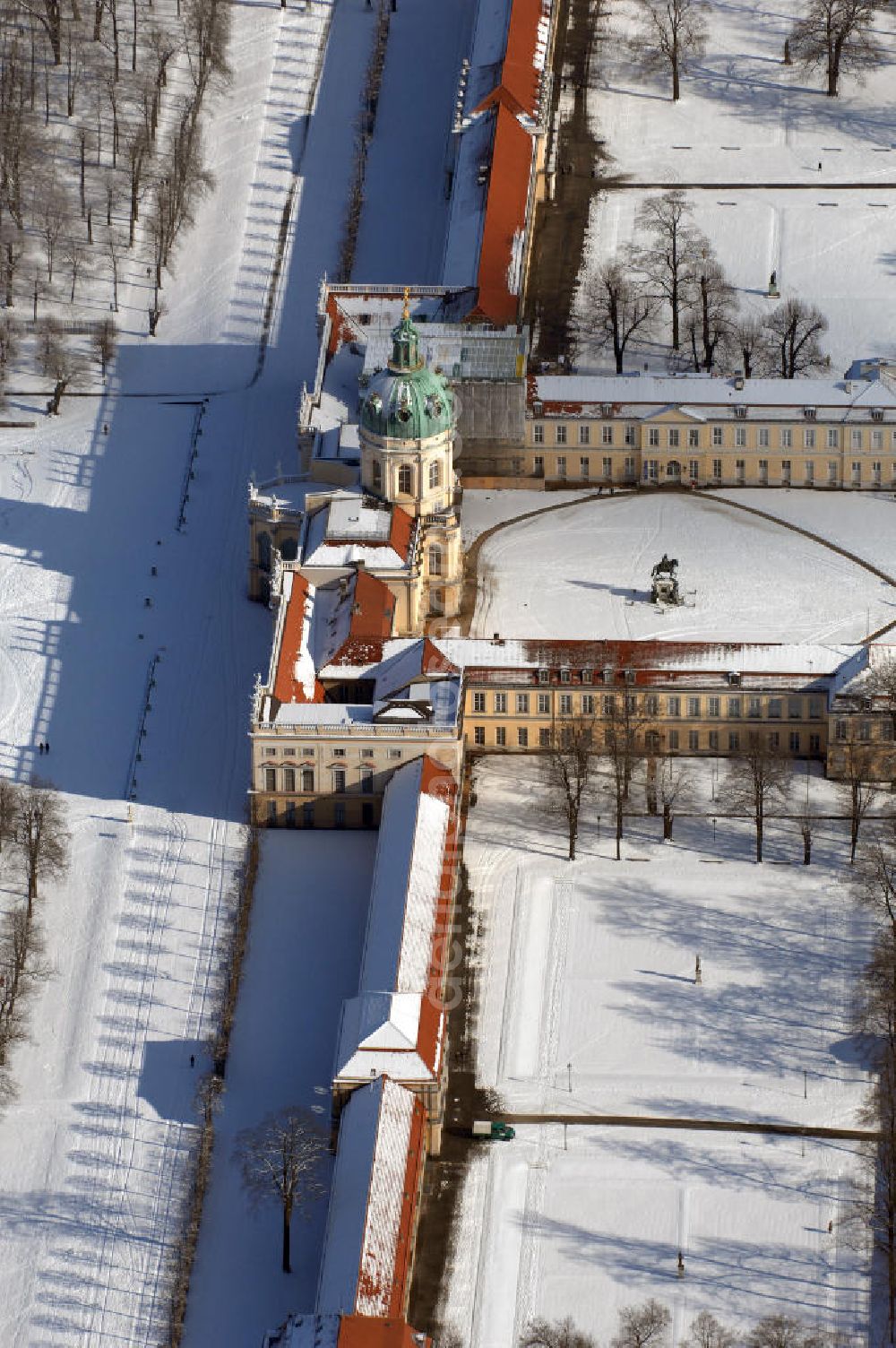 Berlin from the bird's eye view: Blick auf den winterlich verschneite Schloß Charlottenburg. Die spätere Schlossinsel Köpenick wurde schon zu urgeschichtlicher Zeit besiedelt und ist neben Spandau und Cölln eine der frühesten Siedlungsgebiete des heutigen Berlins. Hier fanden sich später slawische Burgwälle, eine slawische Burg entstand im 8. oder 9. Jahrhundert. Mehrere Nachfolgebauten folgten, darunter auch eine spätmittelalterliche Kastellburg. Der Slawenfürst Jaxa von Köpenick regierte hier im 12. Jahrhundert.Für Kurprinz Friedrich (später Kurfürst Friedrich III. von Brandenburg, dann auch König Friedrich I. in Preußen) wurde das Schloss ab 1677 erweitert. Als Architekt war hierbei Rutger van Langervelt, ein geborener Holländer aus Nimwegen, verantwortlich. Der nördliche Pavillon entstand in den Jahren 1679–1682. Der Architekt Johann Arnold Nering folgte van Langervelt 1684 beim Schlossbau und ließ den Wirtschaftsflügel mit der reformierten Schlosskirche (eingeweiht am 6. Januar 1685) und zuvor bereits das Hoftor (1682) entstehen. Friedrich bewohnte das Schloss später mit seiner Gemahlin Elisabeth Henriette von Hessen-Kassel, die den Anstoß zum Bau der Kirche gegeben haben soll.