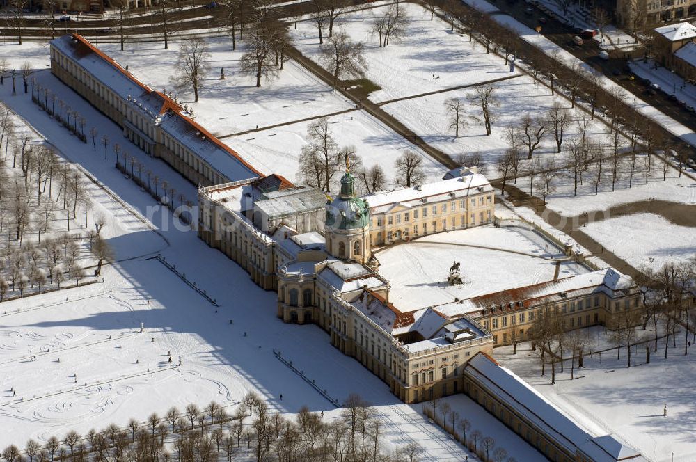 Aerial image Berlin - Blick auf den winterlich verschneite Schloß Charlottenburg. Die spätere Schlossinsel Köpenick wurde schon zu urgeschichtlicher Zeit besiedelt und ist neben Spandau und Cölln eine der frühesten Siedlungsgebiete des heutigen Berlins. Hier fanden sich später slawische Burgwälle, eine slawische Burg entstand im 8. oder 9. Jahrhundert. Mehrere Nachfolgebauten folgten, darunter auch eine spätmittelalterliche Kastellburg. Der Slawenfürst Jaxa von Köpenick regierte hier im 12. Jahrhundert.Für Kurprinz Friedrich (später Kurfürst Friedrich III. von Brandenburg, dann auch König Friedrich I. in Preußen) wurde das Schloss ab 1677 erweitert. Als Architekt war hierbei Rutger van Langervelt, ein geborener Holländer aus Nimwegen, verantwortlich. Der nördliche Pavillon entstand in den Jahren 1679–1682. Der Architekt Johann Arnold Nering folgte van Langervelt 1684 beim Schlossbau und ließ den Wirtschaftsflügel mit der reformierten Schlosskirche (eingeweiht am 6. Januar 1685) und zuvor bereits das Hoftor (1682) entstehen. Friedrich bewohnte das Schloss später mit seiner Gemahlin Elisabeth Henriette von Hessen-Kassel, die den Anstoß zum Bau der Kirche gegeben haben soll.