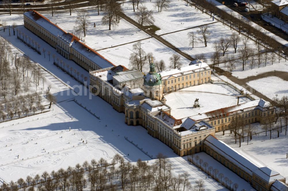 Aerial photograph Berlin - Blick auf den winterlich verschneite Schloß Charlottenburg. Die spätere Schlossinsel Köpenick wurde schon zu urgeschichtlicher Zeit besiedelt und ist neben Spandau und Cölln eine der frühesten Siedlungsgebiete des heutigen Berlins. Hier fanden sich später slawische Burgwälle, eine slawische Burg entstand im 8. oder 9. Jahrhundert. Mehrere Nachfolgebauten folgten, darunter auch eine spätmittelalterliche Kastellburg. Der Slawenfürst Jaxa von Köpenick regierte hier im 12. Jahrhundert.Für Kurprinz Friedrich (später Kurfürst Friedrich III. von Brandenburg, dann auch König Friedrich I. in Preußen) wurde das Schloss ab 1677 erweitert. Als Architekt war hierbei Rutger van Langervelt, ein geborener Holländer aus Nimwegen, verantwortlich. Der nördliche Pavillon entstand in den Jahren 1679–1682. Der Architekt Johann Arnold Nering folgte van Langervelt 1684 beim Schlossbau und ließ den Wirtschaftsflügel mit der reformierten Schlosskirche (eingeweiht am 6. Januar 1685) und zuvor bereits das Hoftor (1682) entstehen. Friedrich bewohnte das Schloss später mit seiner Gemahlin Elisabeth Henriette von Hessen-Kassel, die den Anstoß zum Bau der Kirche gegeben haben soll.